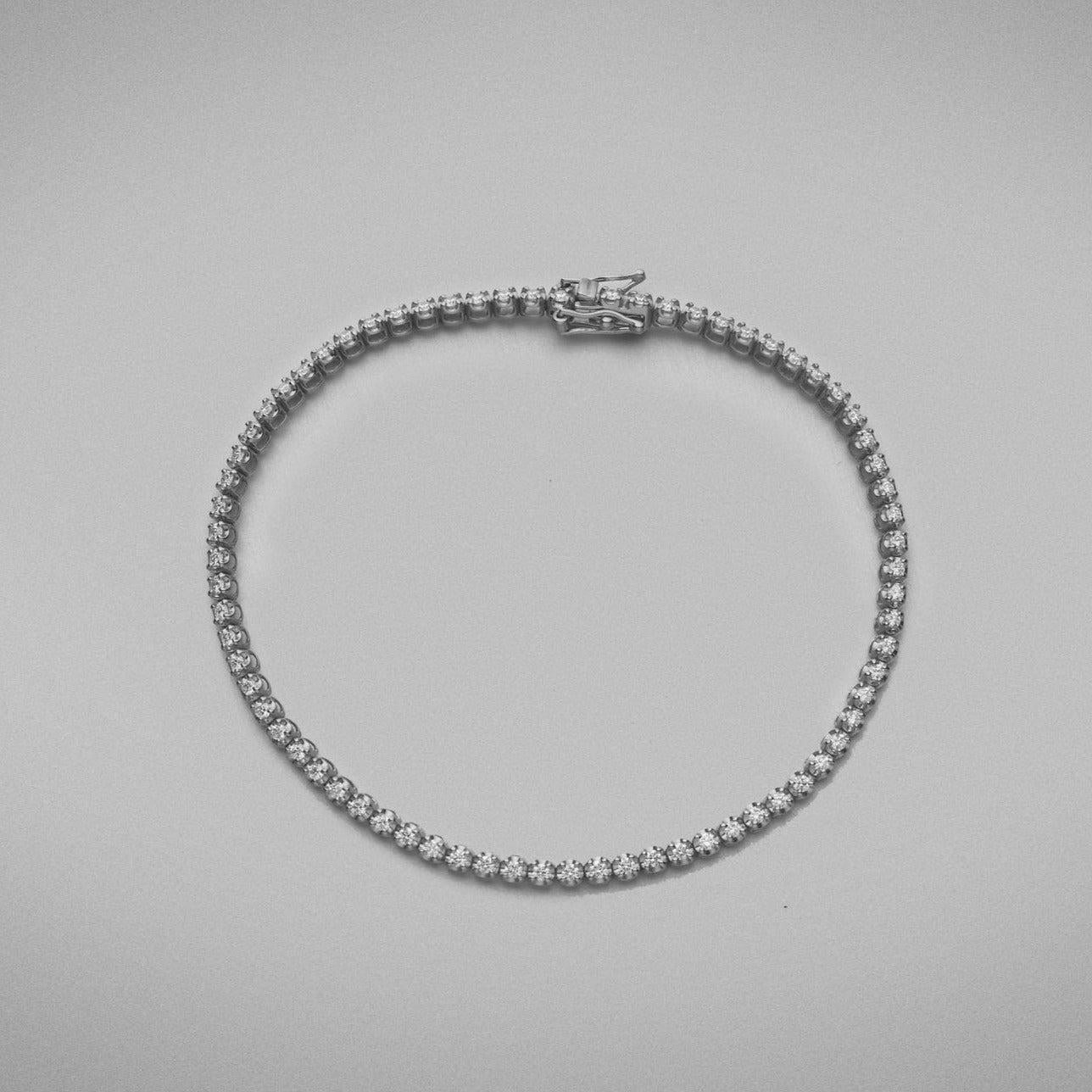 A BUNDA 'Tennis' bracelet in 18ct white gold. The bracelet is set with round brilliant diamonds in castle claw settings. Bracelet is stamped 'BUNDA'.

Characteristics of Round Brilliant Cut Diamonds: 87 = .69ct, F colour, VS Clarity

Total weight of