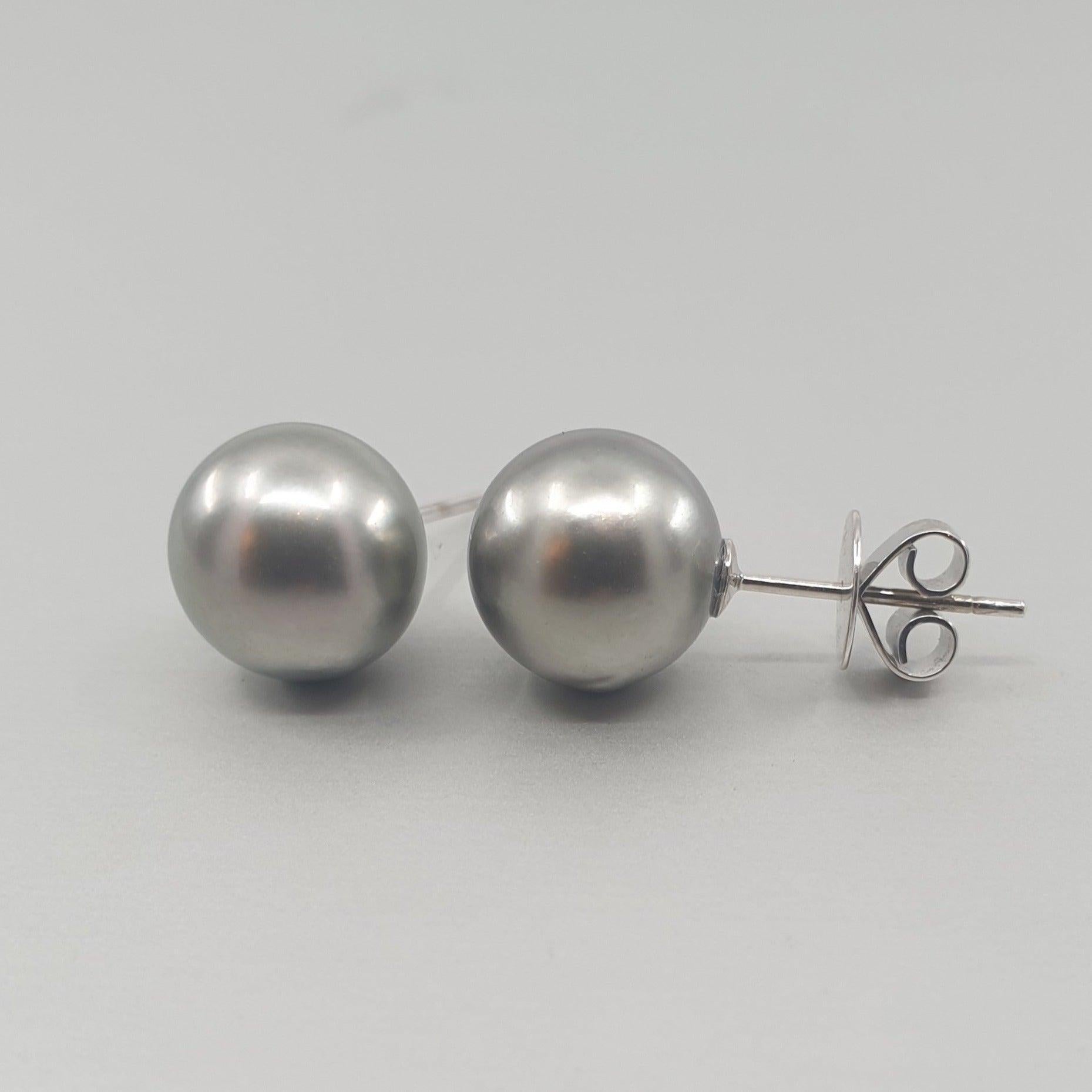 A pair of BUNDA 'Studs' in 18ct white gold. Each stud is set with a Tahitian pearl, 10.30mm round in shape, silver grey in colour, with clear skin and excellent luster. The fittings are post and butterfly. Butterflies are stamped
