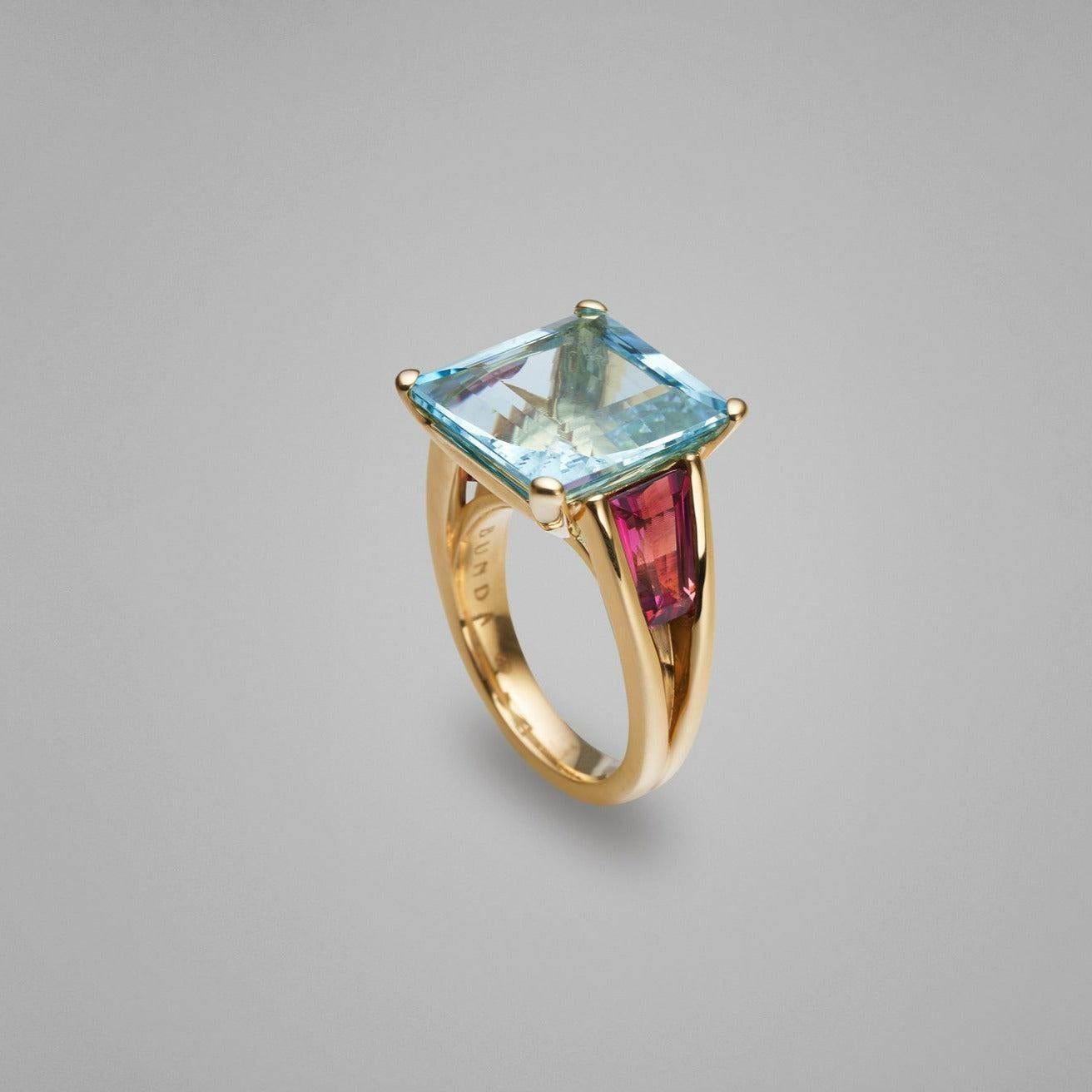 BUNDA 'Bundova' aquamarine and rubelite ring featuring rare and impressive octagonal cut aquamarine weighing 11.05cts. Handcrafted in 18ct yellow gold this ring features large tapered baguette rubelite tourmaline shoulder stones set within round