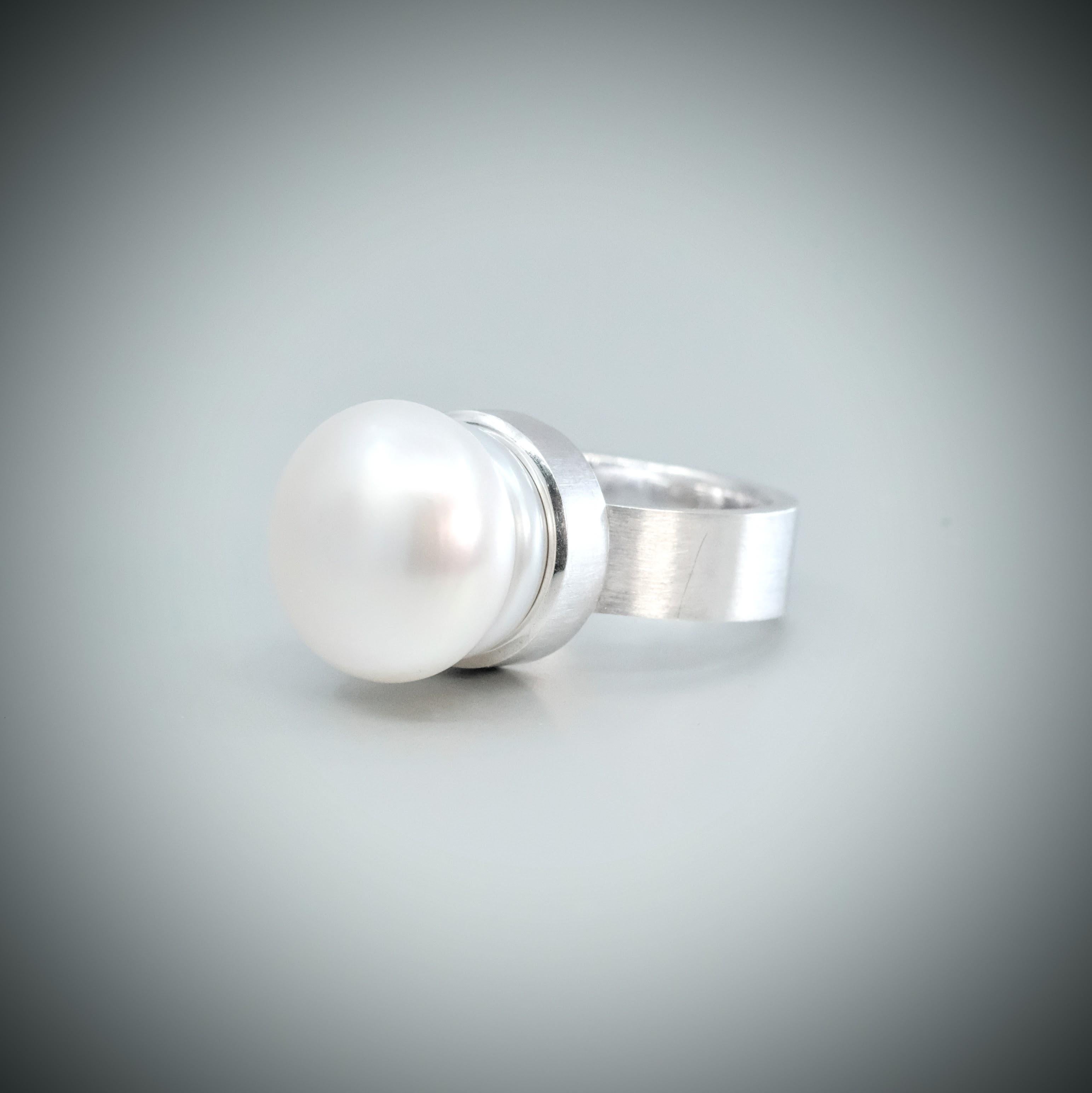 A BUNDA 'Corvus' Cultured South Sea pearl ring in sterling silver, featuring a circle South Sea pearl.

The pearl measures approximately 14.15mm in diameter, is white in colour with an excellent lustre.

Total weight: 11.53 grams.

Size L 