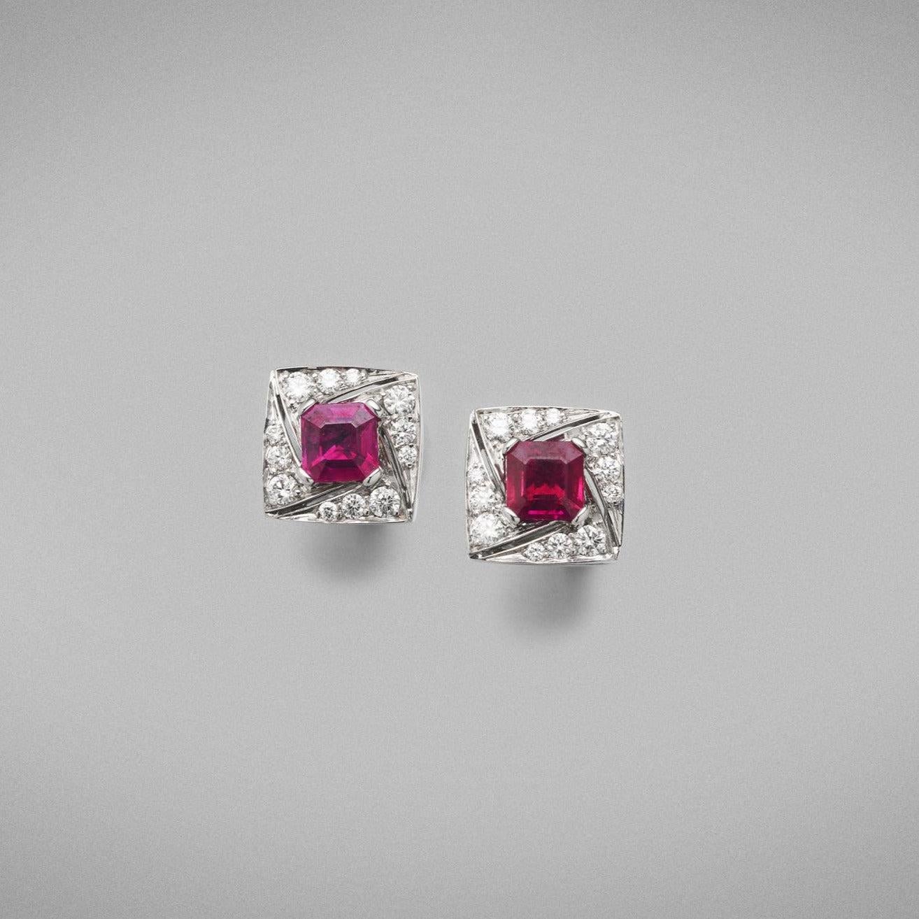 A pair of BUNDA 'Arya' Ruby and earrings in 18 carat white gold, featuring a pair of Asscher cut rubies, claw set to the centre and surrounded with thread-set round brilliant cut diamonds, with a post and butterfly fitting.

Characteristics of Ruby: