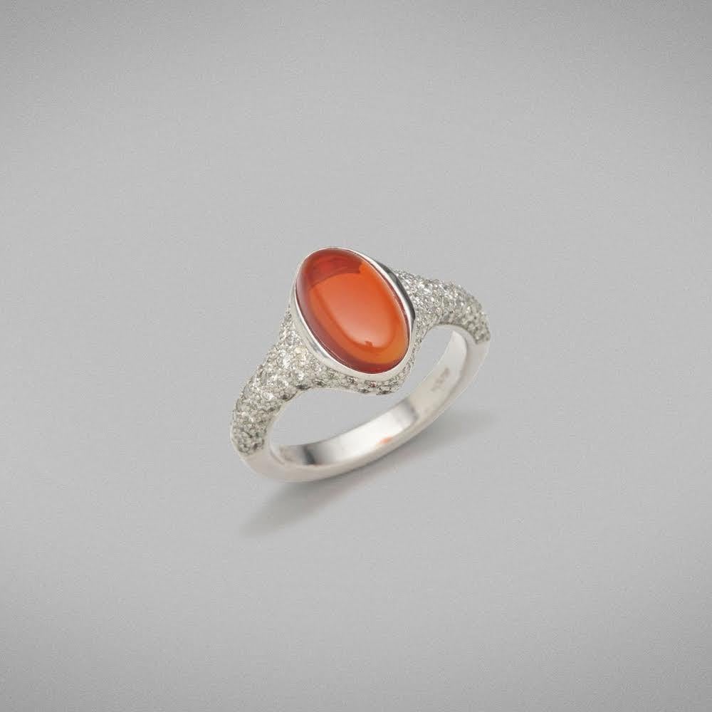 A BUNDA 'Pavo' ring in 18ct white gold, featuring a bezel set, rich orange, Volcanic opal, and pave set, round brilliant cut diamonds.

Characteristics of Volcanic Opal: 1 = 1.78ct.

Characteristics of diamonds: 105 = 0.93ct, F colour, VS clarity.