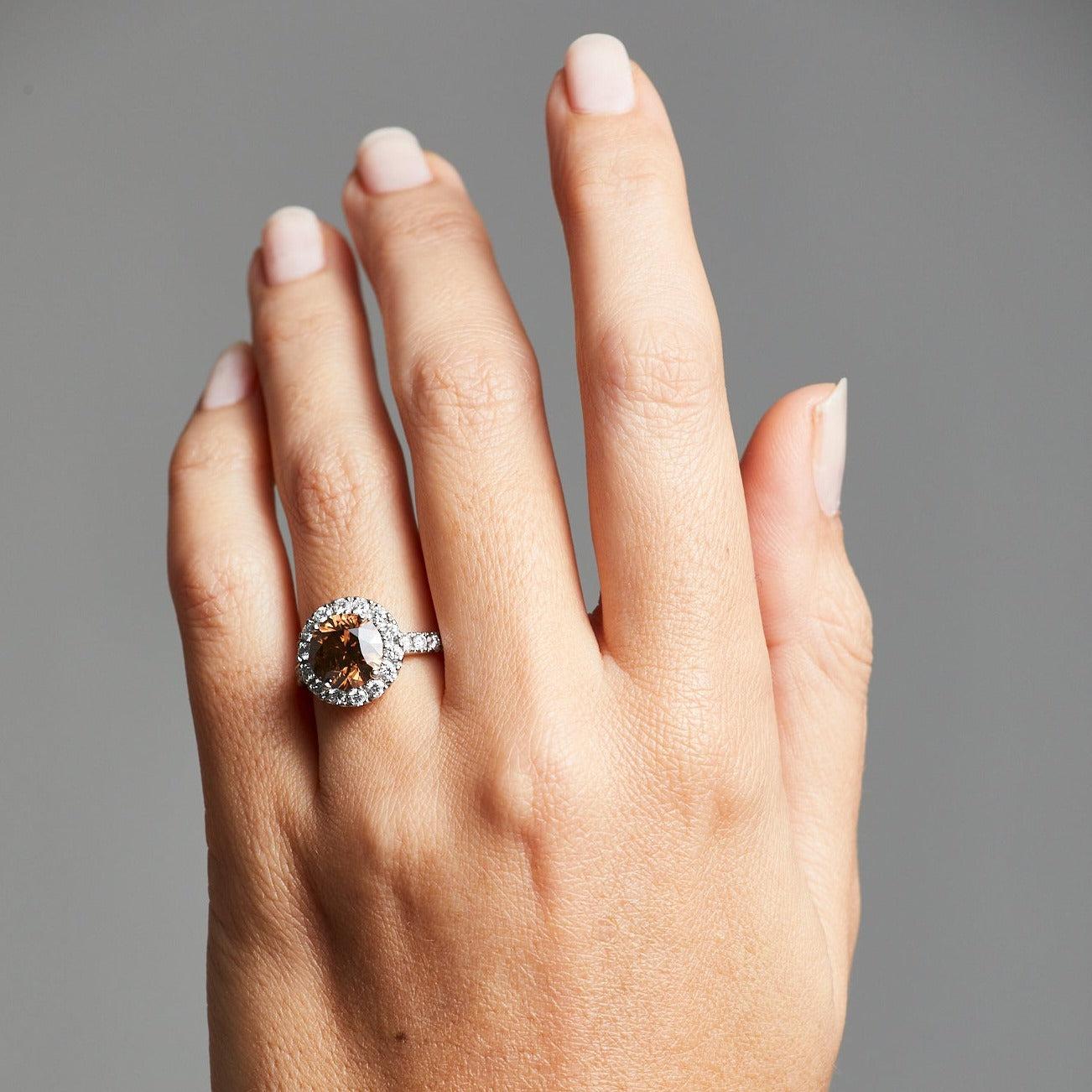 A BUNDA 'Valentin' diamond ring in platinum, 4 claw set with a round brilliant cut cognac diamond, surrounded with castleset round brilliant cut white diamonds to the head and
shoulders.
Characteristics of cognac diamond: 1 = 3.01 carats,