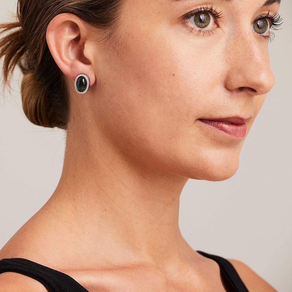 A pair of BUNDA 'Corvus' tourmaline earrings in 18ct white gold, featuring a pair of cabochon cut blue/green tourmalines, bezel set and surrounded with threadset round brilliant cut diamonds, fitted with a post and keyhole clip fitting.

Weight of