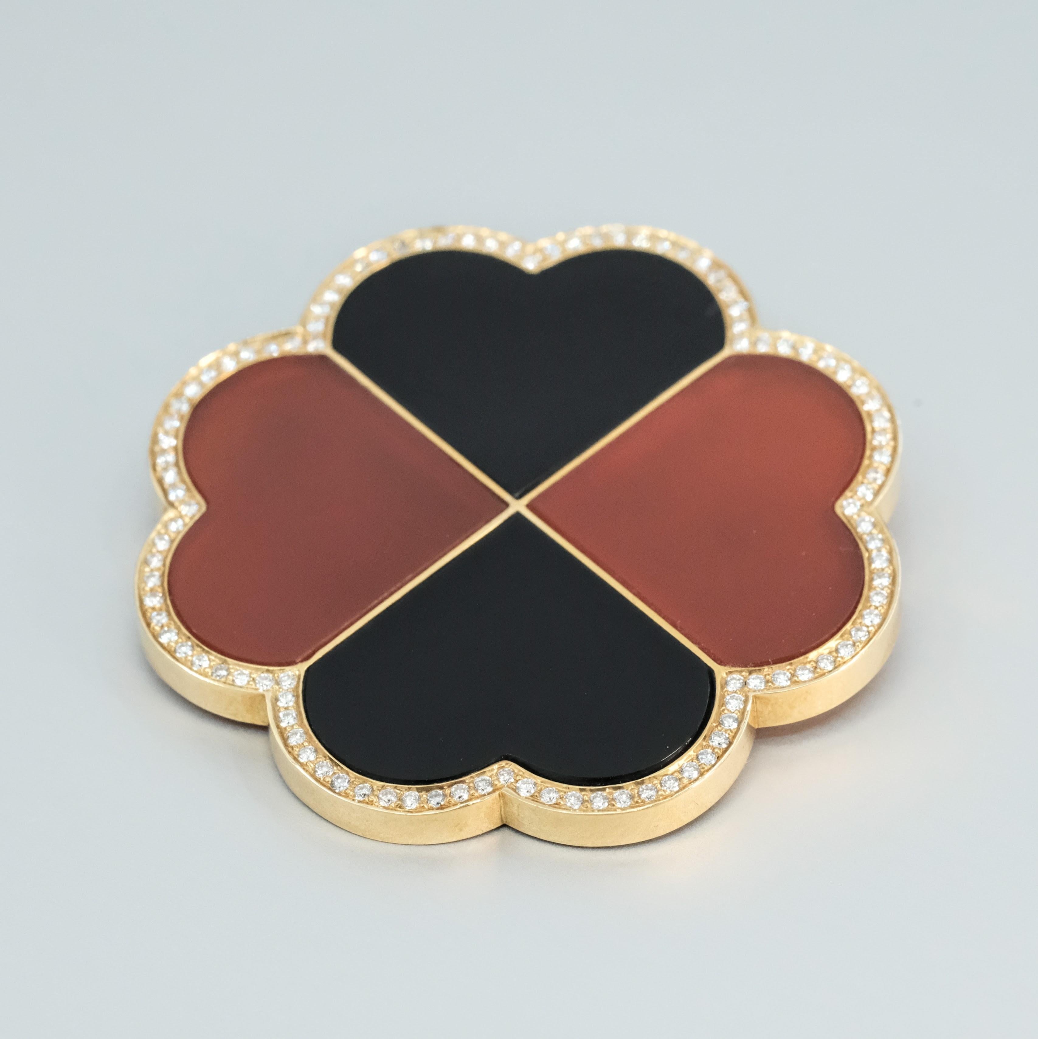 A BUNDA 'Couture' Onyx, Carnelian and diamond brooch made in 18 carat yellow gold, featuring specially cut Onyx and Carnelian stones, surrounded with threadset round brilliant cut diamonds.

Estimated weight of Onyx and Carnelian: 4 =