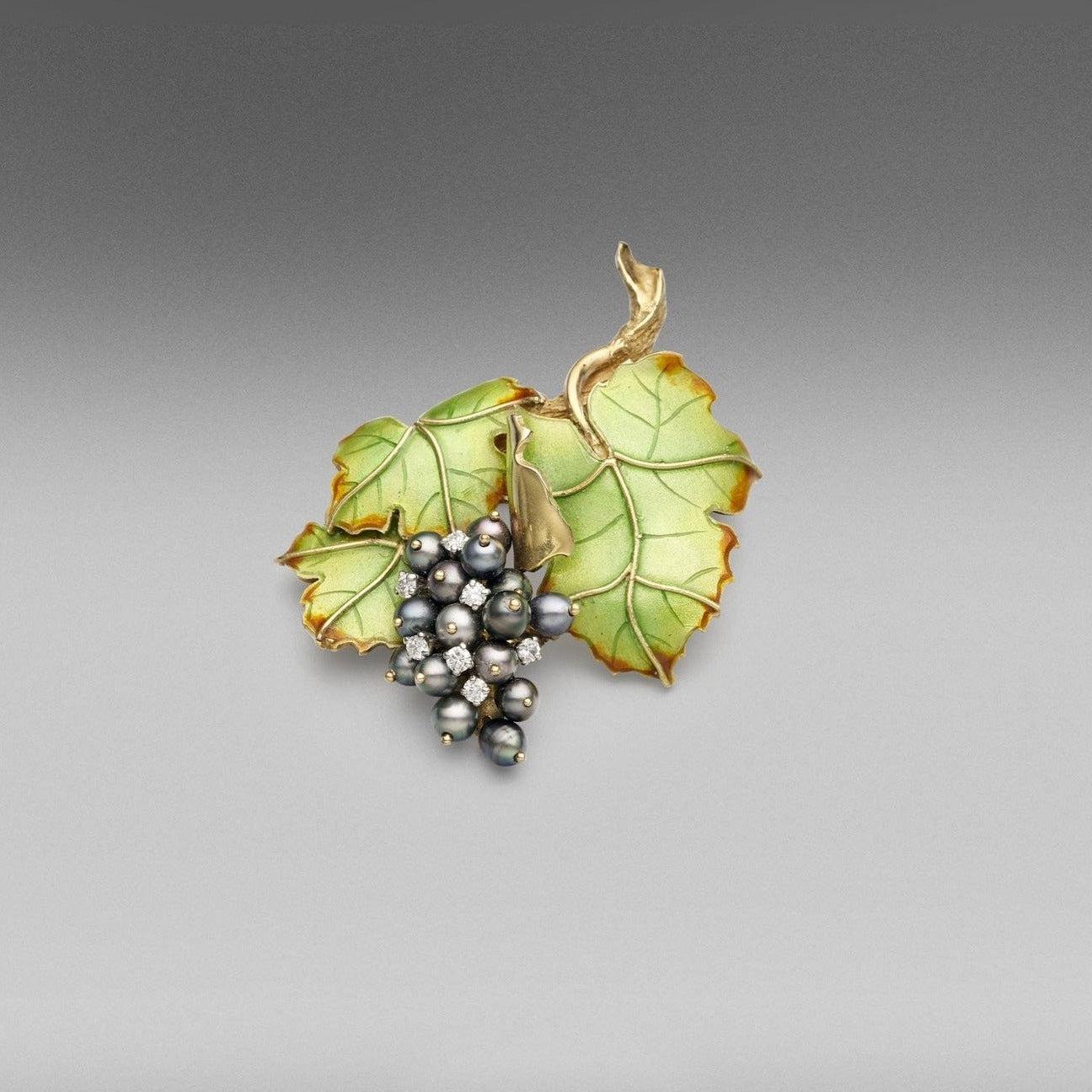 Broche 'Couture' en platine et or jaune 18 carats, ornée de perles de culture de Tahiti de forme baroque, de diamants ronds de taille brillant et de feuilles d'émail.

Dimensions de la perle : 5.00mm Poids des perles : 15 = 0.21