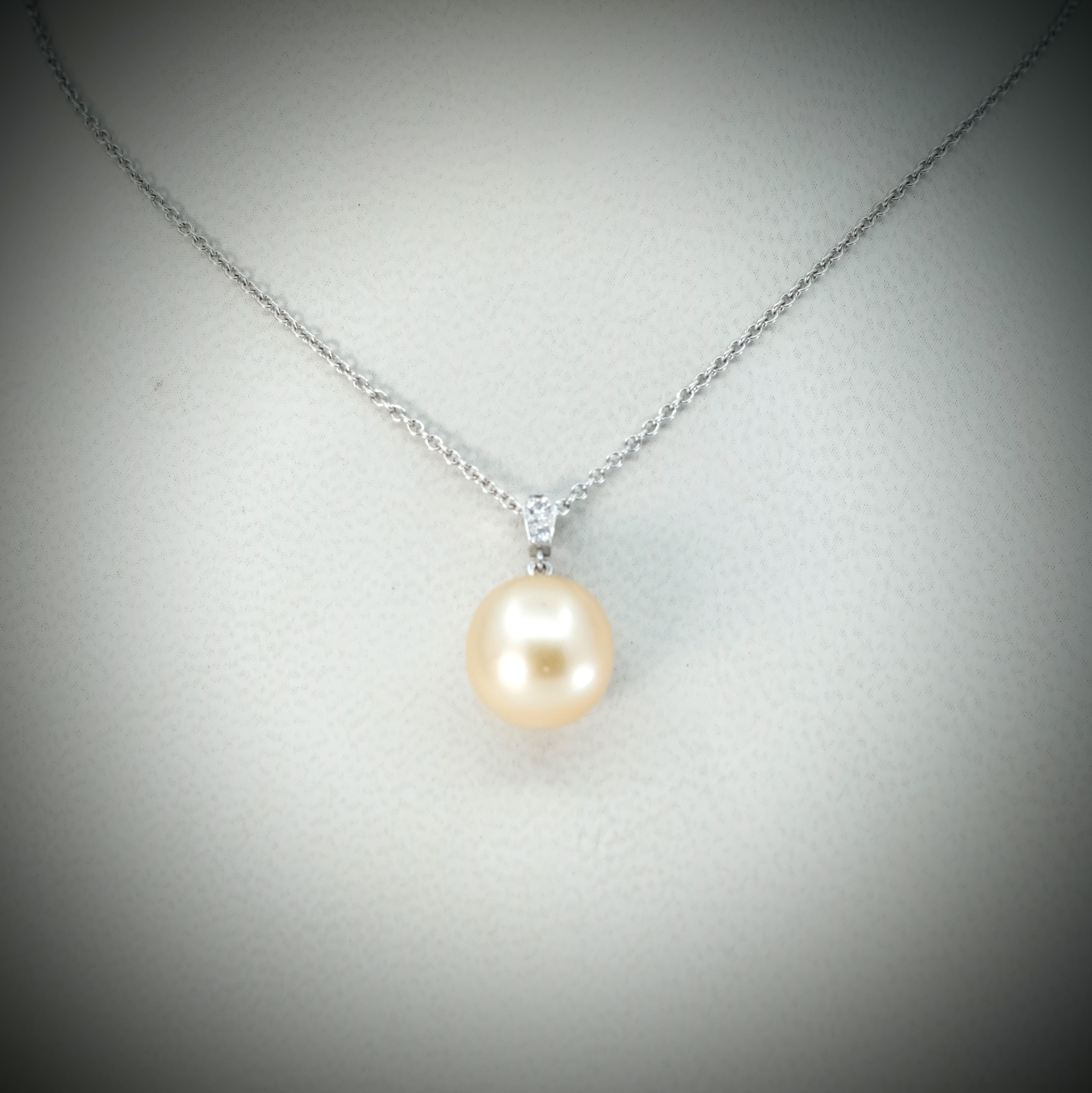 A BUNDA Cultured South Sea pearl and diamond 'Russe' pendant in 18 carat white gold, featuring a slight drop shaped golden pearl of clean skin and excellent lustre.

Dimensions of pearl: 10.49 - 10.57mm

Characteristics of diamonds: 2 = 0.03ct, F