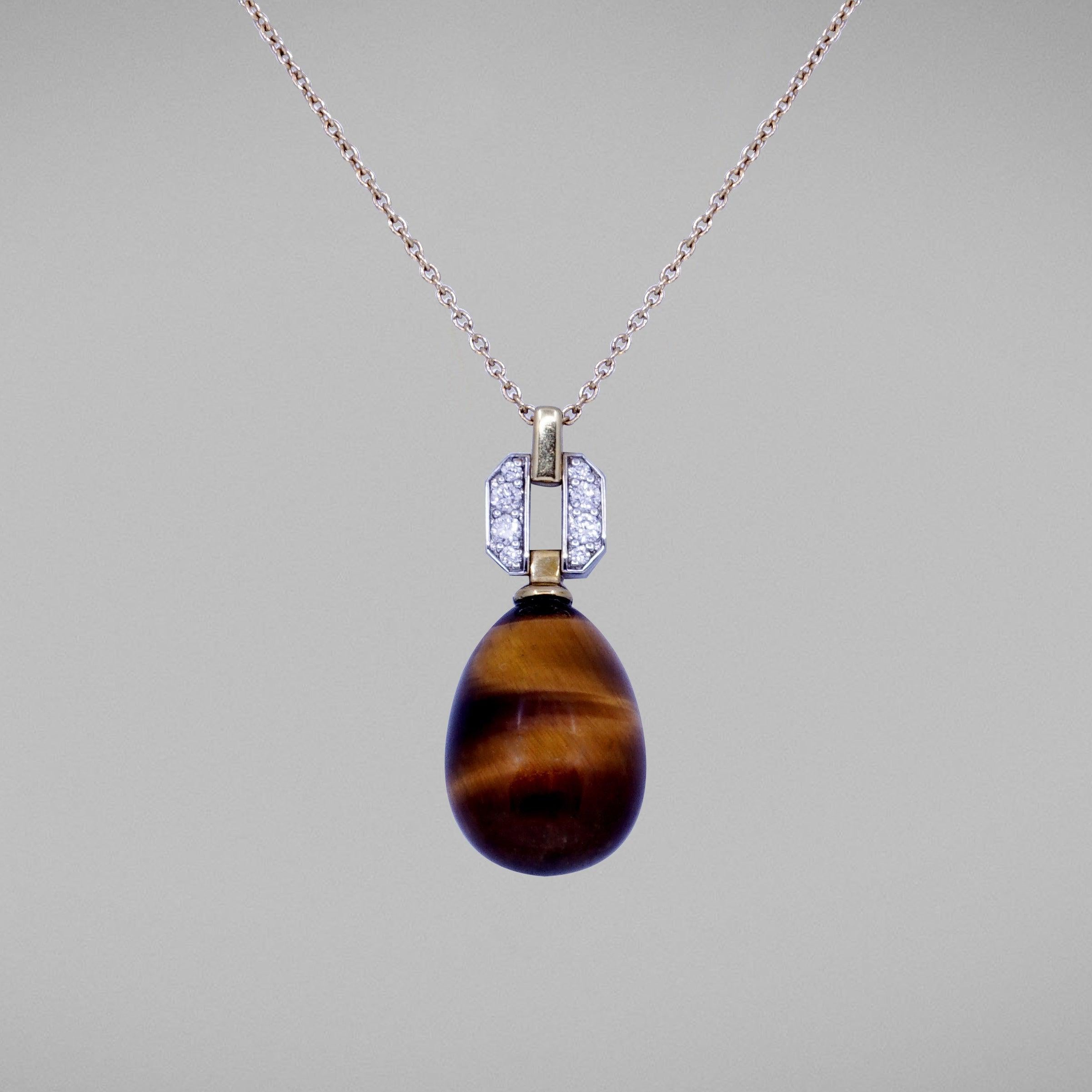 A BUNDA 'Hollywood' pendant in 18ct white and 18ct yellow gold featuring a Tigers Eye drop fitted below a
threadset, round brilliant cut diamond pendant mount with an 18ct yellow gold trace chain.
Characteristics of Tiger's Eye; 2x Brown Orange