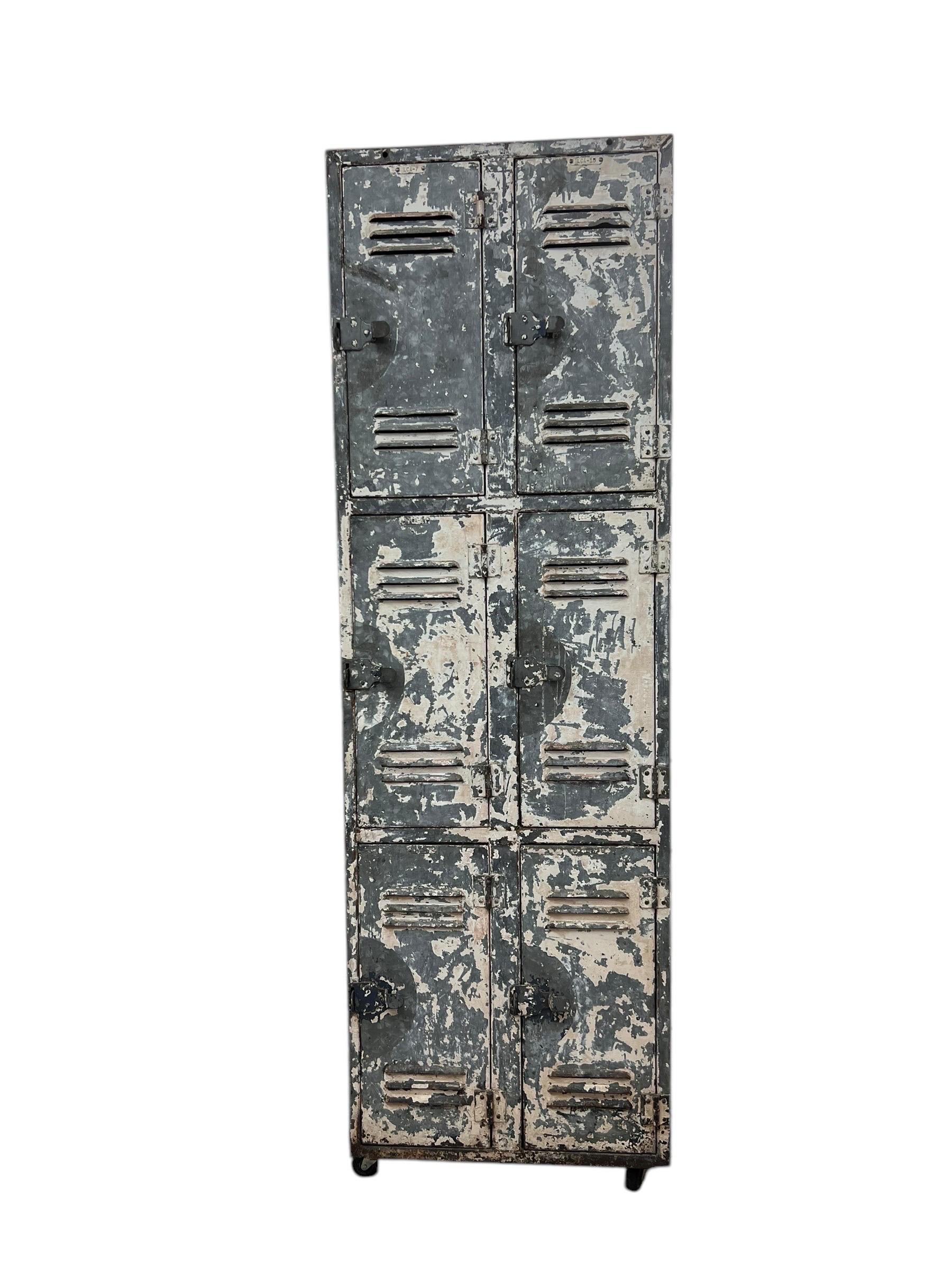 Dieser Metallschrank im Vintage-Stil hat ein hohes, schlankes Design mit 6 Fächern. Das Äußere weist eine beschädigte Oberfläche mit abblätternder Farbe auf, was auf eine Geschichte des Gebrauchs und der Abnutzung hindeutet, die dem Stück Charakter