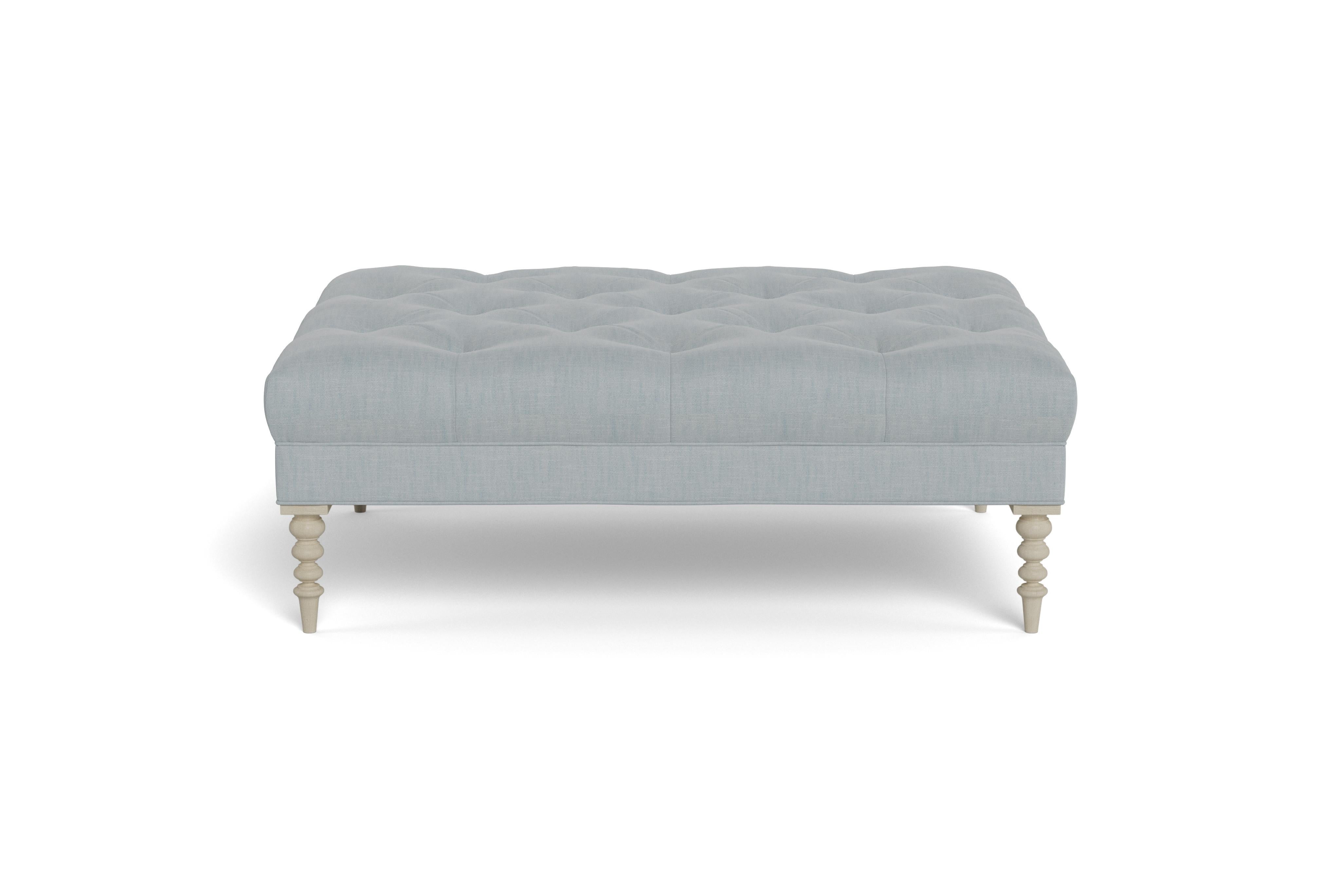 A large cocktail ottoman, with beautiful tufting set atop a trim upholstered box, with wonderfully turned legs. Made to order in a neutral sky performance linen, a fabric able to be cleaned and used in high traffic areas.  Legs finished in alpine