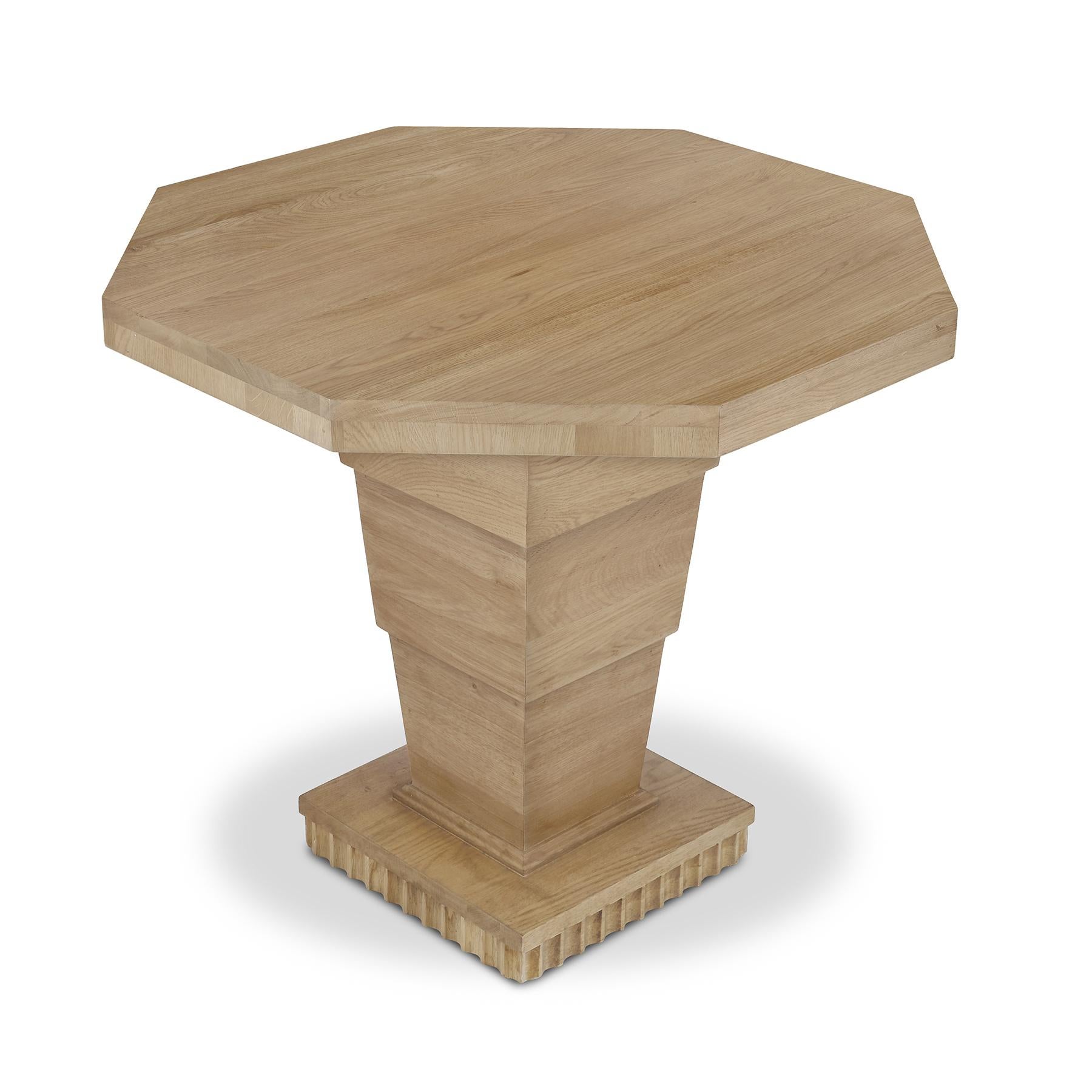 Una mesa auxiliar tranquilizadoramente sólida, de generosas dimensiones para ayudar a anclar sofás y sillas por igual, fabricada en cálido roble, presenta un práctico tablero de forma octogonal, apoyado en un pedestal escalonado sobre una base