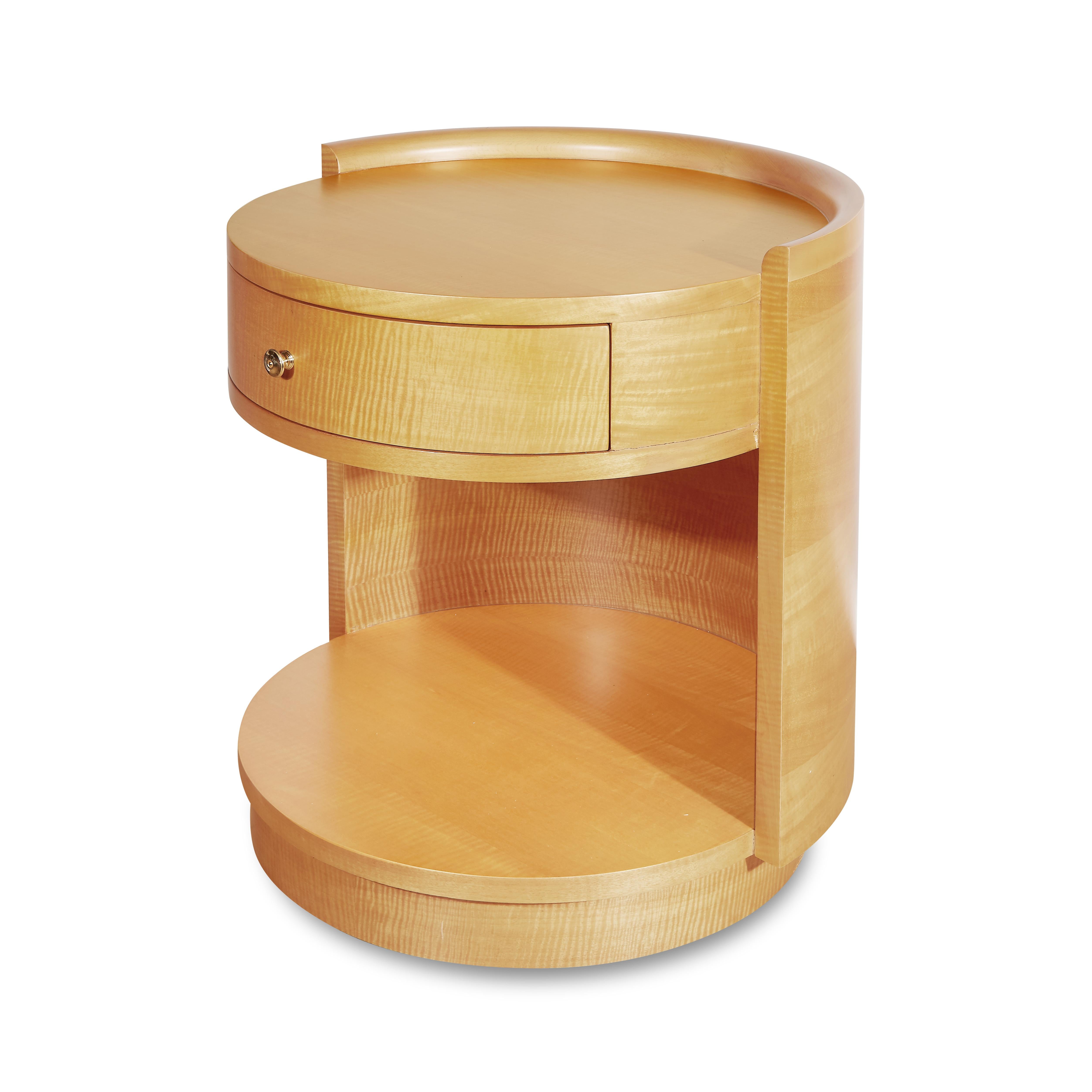 A wonderfully sleek yet capacious table, its circular form is elevated upon a plinth, with a crescent wrap around its back. Featuring a warm, subtle Birch veneer and beautifully cast brass drawer knob. Works equally well as a bedside table or as a