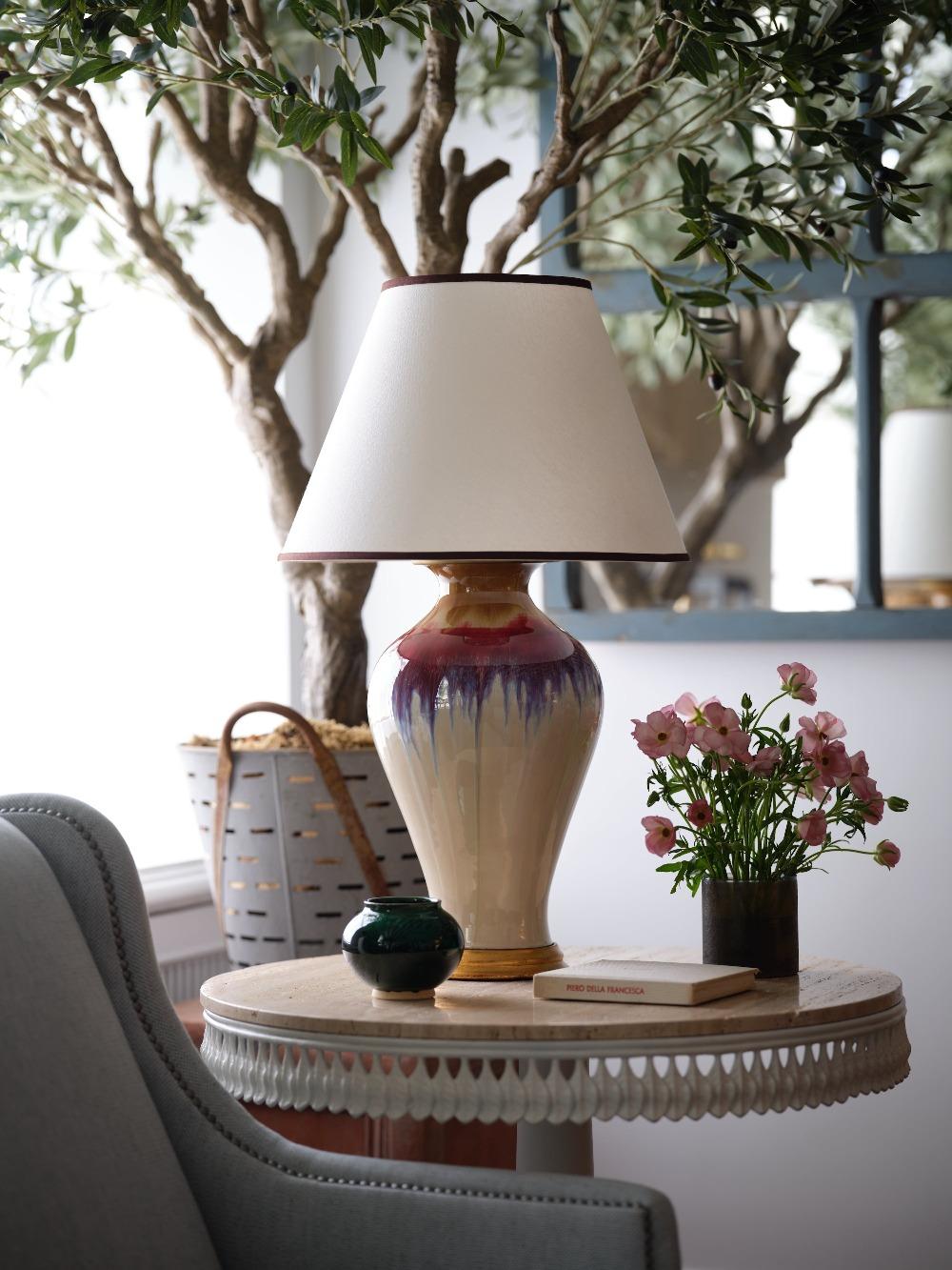Rich tones of strawberry and calm shades of doe fall across the curvaceous form—traditionally called a plum shape--​of our Flambe lamp, mounted atop a gold base.

This lamp’s flamboyant glaze takes inspiration from traditional flambé glazes which