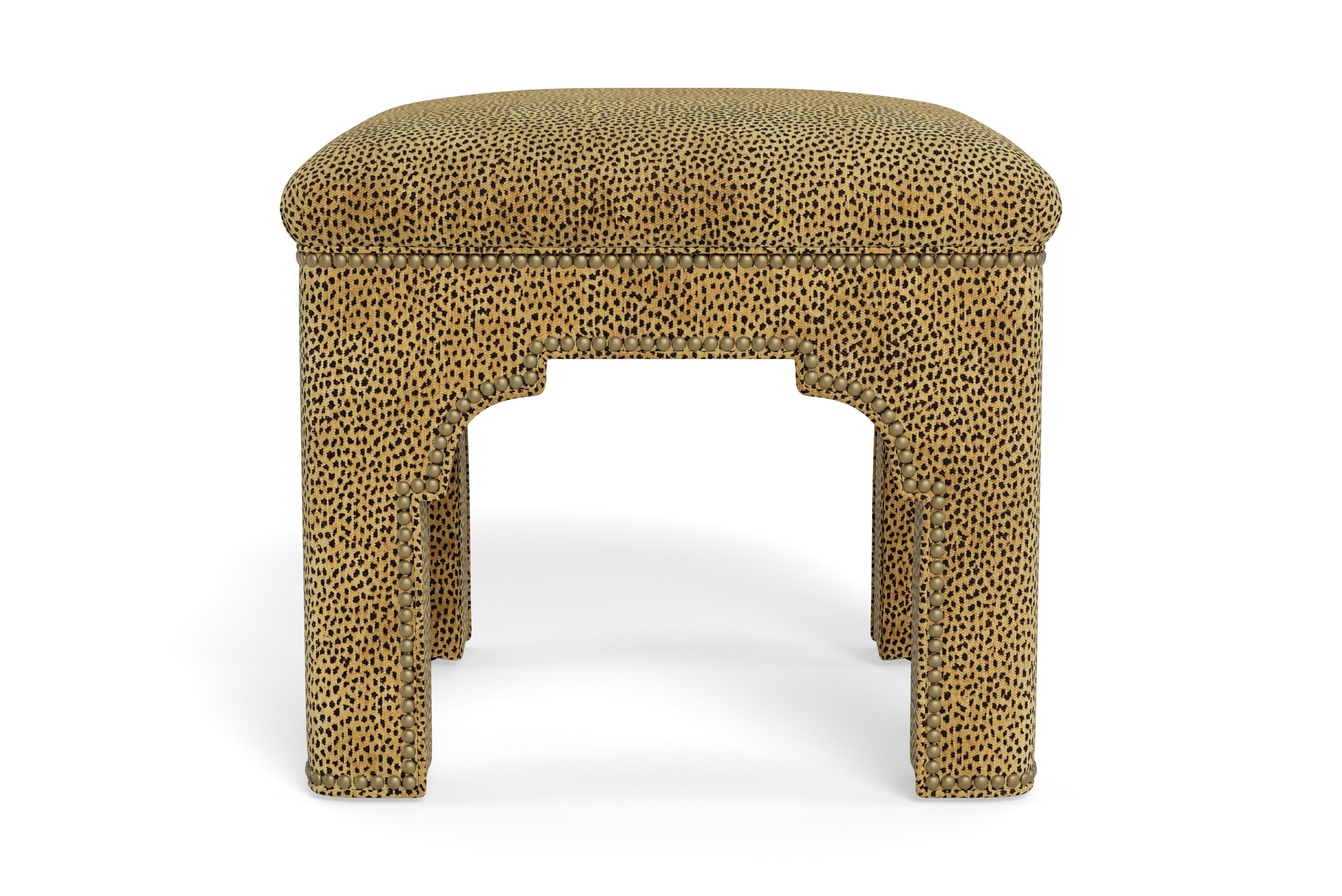 Add a chic accent to any room with this compact stool on its own or displayed in pairs.  Made to order in natural leopard chenille with antique brass nail heads. The tightly upholstered seat covers a solid maple frame. A Mughal-inspired arch make it