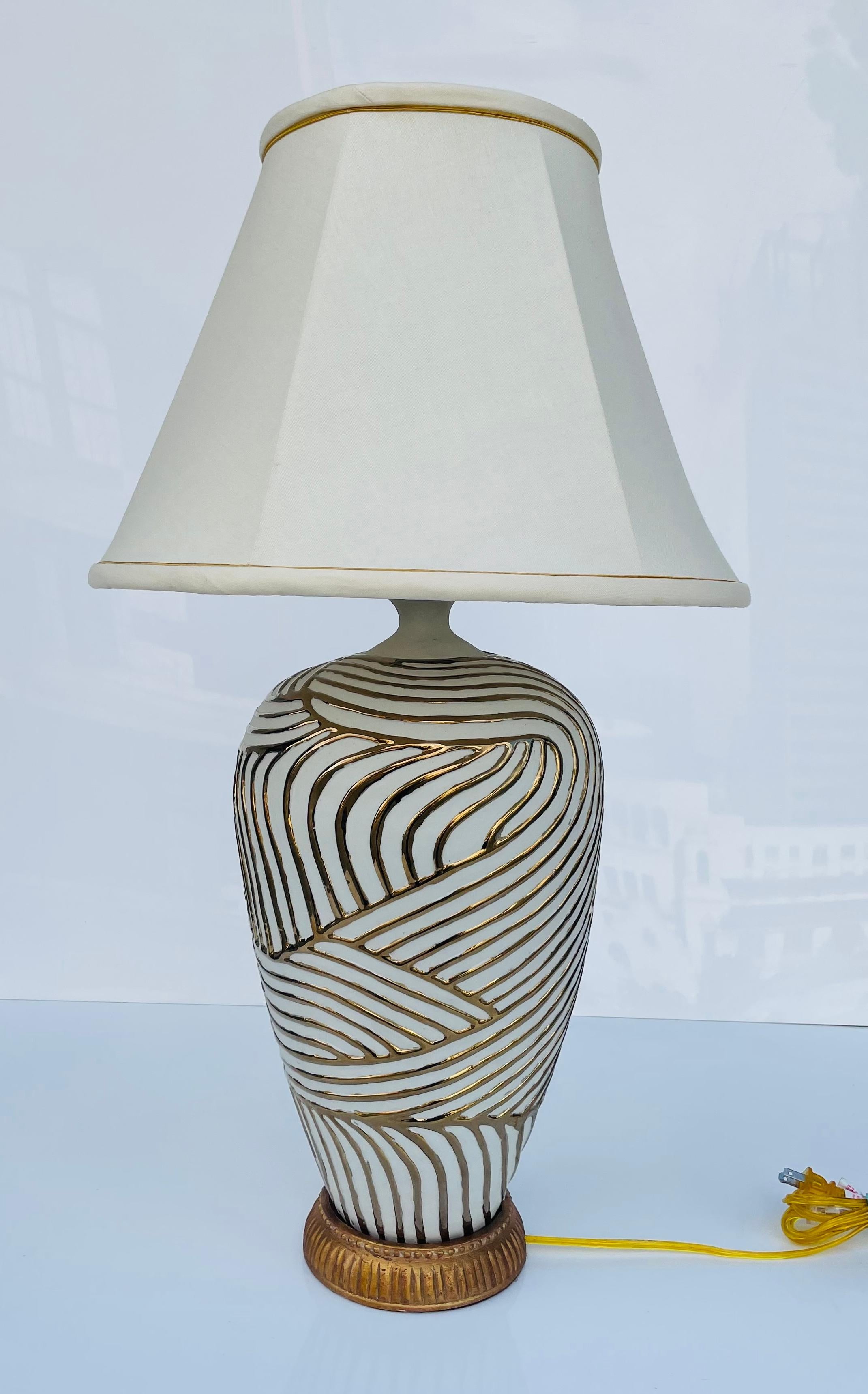 Bunny Williams combines classic design with a modern vision for the most exquisite home décor of the utmost quality. Bold but sophisticated, this eye-catching lamp is composed of an Asian ceramic urn with textured gold lines. A hand-carved giltwood