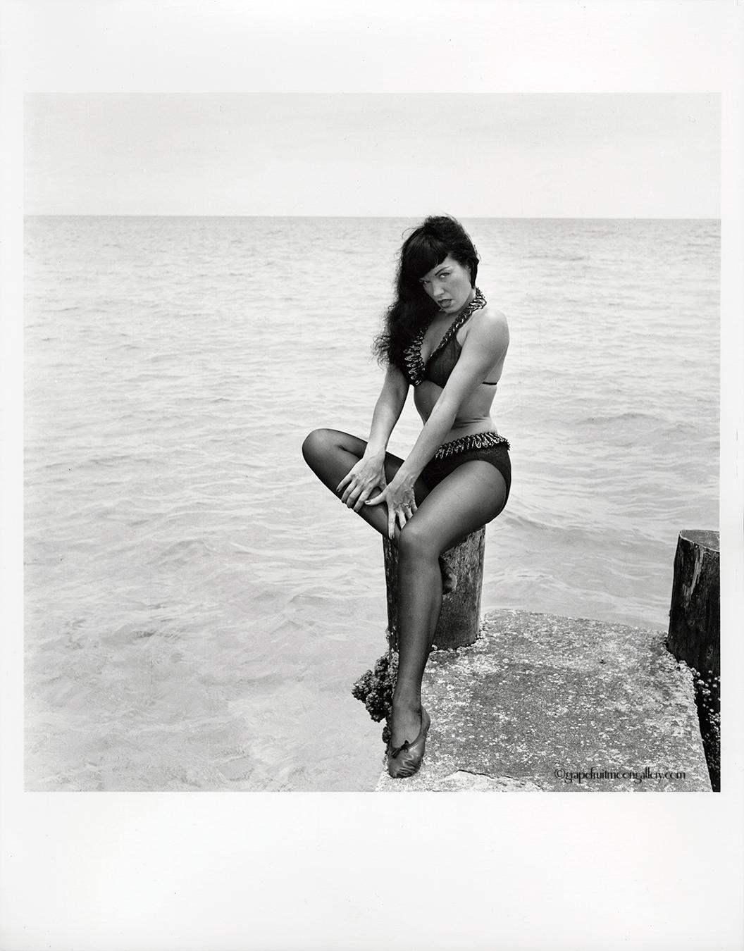 Bettie Page Seated on Pier - Photograph by Bunny Yeager