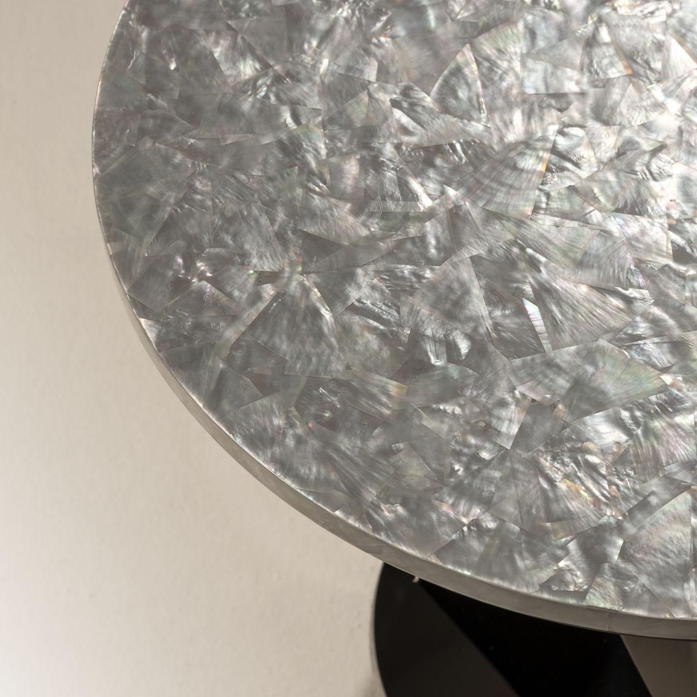 So dynamic it almost looks like frozen in the middle of a pirouette, the base of this round side table brims with sculptural charm. Its gun-metal-gray finish stands in neat contrast with the circular top that, crafted of mat-finished nacre, amazes