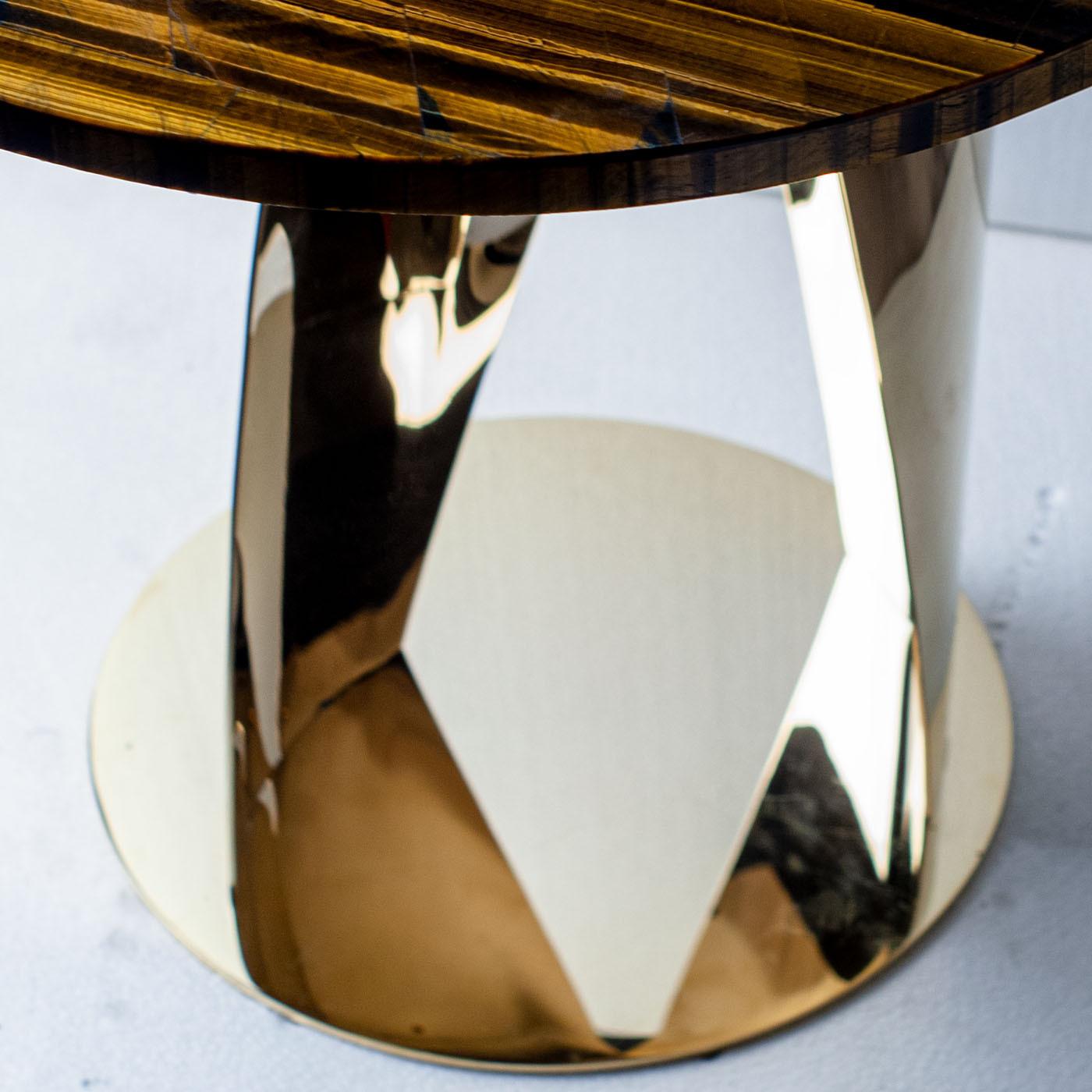 A circular tiger-eye top, stupefying with the intensity and warmth of its veins, is the focal element of this sophisticated side table. A splendid addition to a wide variety of interior decors' corners needing a boost of personality, its design is