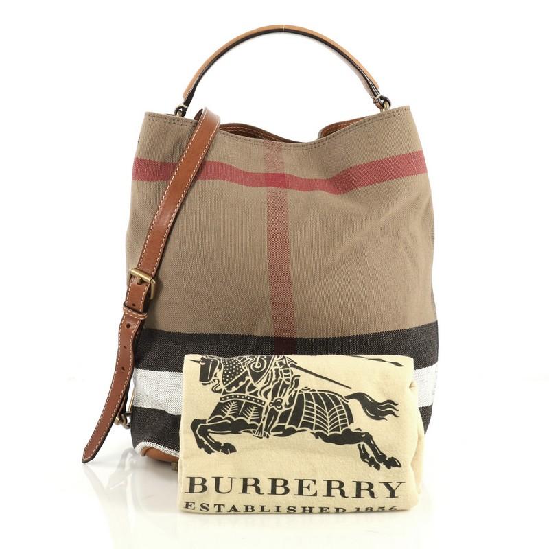This Burberry Ashby Handbag House Check Canvas Medium, crafted in brown house check canvas, features a single looped leather handle and aged gold-tone hardware. It opens to a brown house check canvas interior. 

Estimated Retail Price: