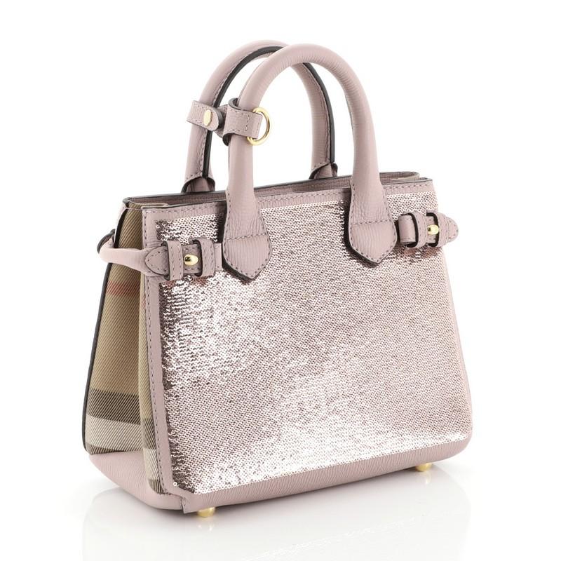This Burberry Banner Convertible Tote Sequin with Leather and House Check Canvas Baby, crafted in pink leather and sequin, features dual-rolled handles, Burberry house check canvas side panels, and gold-tone hardware. Its magnetic snap closure opens