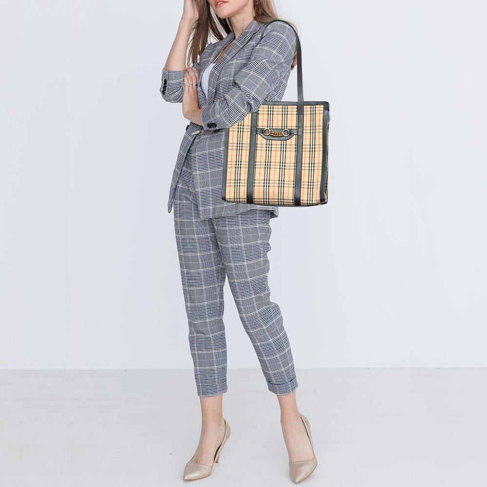 The 1983 Link tote from the House of Burberry is all about luxury. It has a signature Haymarket Check coated canvas & leather exterior with a gold-tone link accent fixated on the front. In addition, this bag comes with a fabric-lined interior and