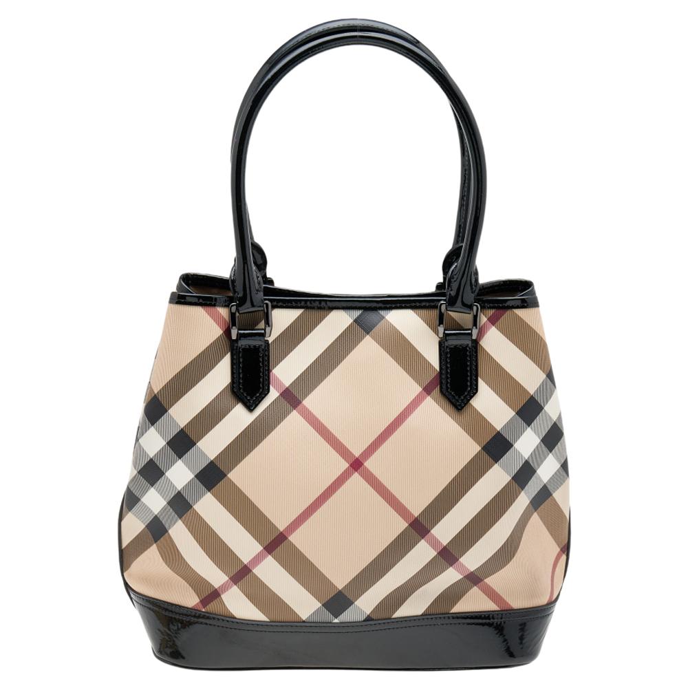 Be it shopping or a day out with family; totes are the best way to carry all your belongings securely. This tote from the House of Burberry will certainly prove helpful to you. It is made from beige-black Nova Check PVC and patent leather. It