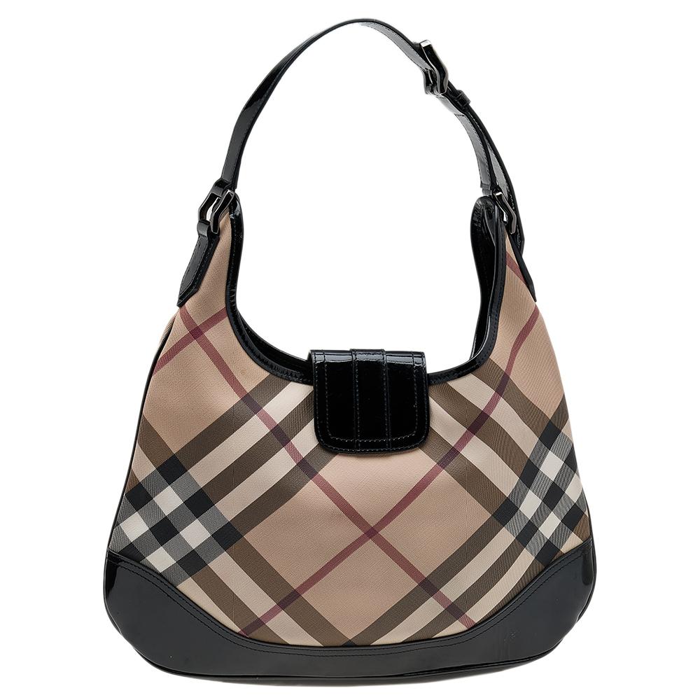 Give your essentials a stylish home with this Burberry Brooke hobo. It is crafted from Super Nova check PVC and patent leather on the exterior. The bag is styled with a buckle flap closure, an adjustable handle, and black-tone hardware. It is lined