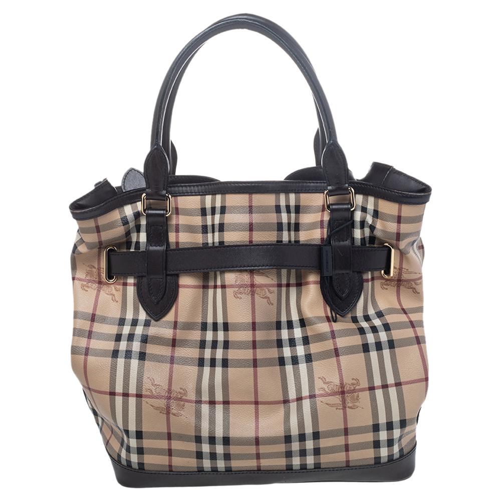 The perfect companion for your everyday looks, this Golderton tote from Burberry is styled in the brand's signature Haymarket check canvas with brown-colored leather trims. The exterior of this lovely bag features a belt detail complete with