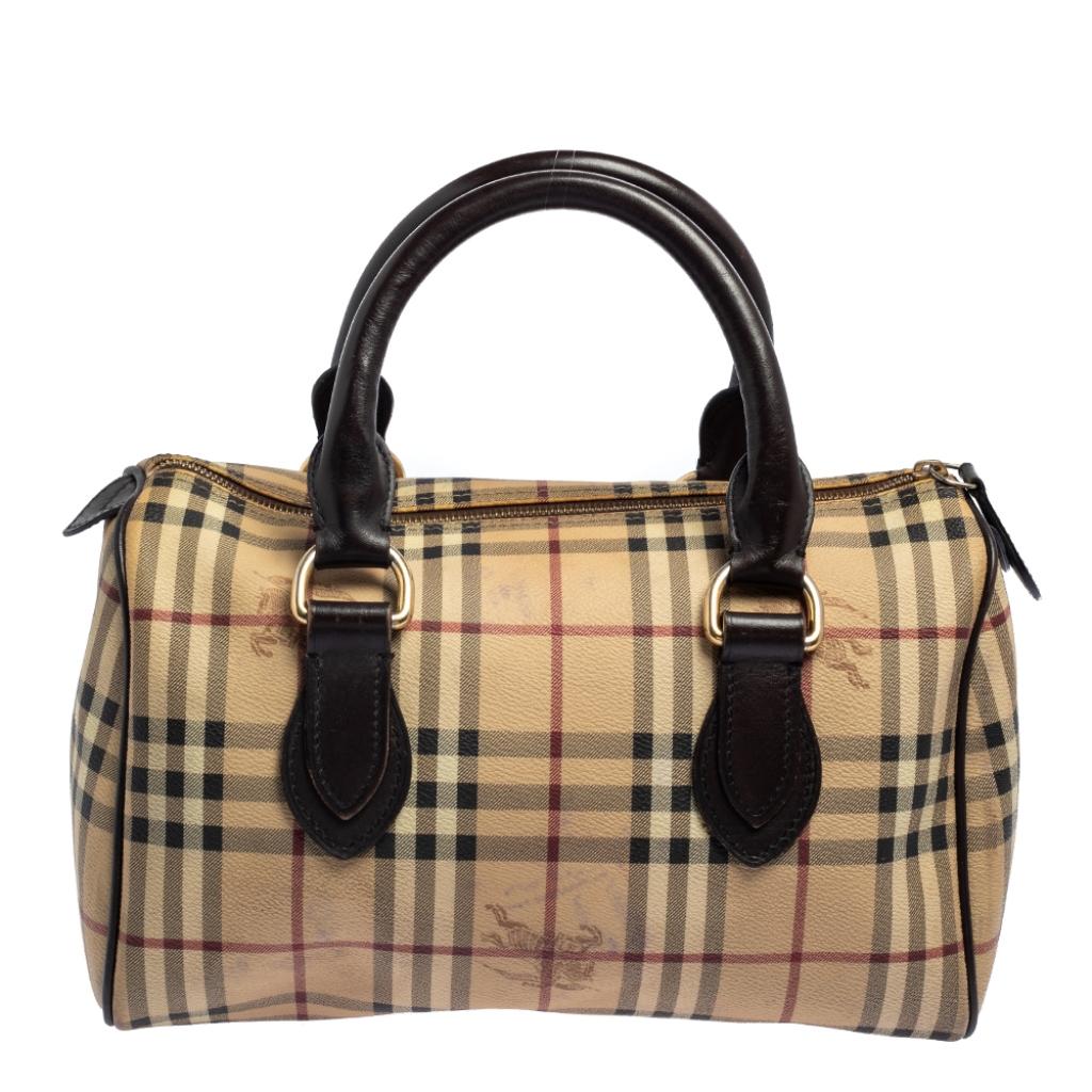 Spacious and handy, this Boston bag from Burberry is a great purchase. It has been crafted using signature Haymarket Check PVC and accented with leather trims and gold-tone hardware. The beige/brown bag is equipped with a well-sized canvas interior