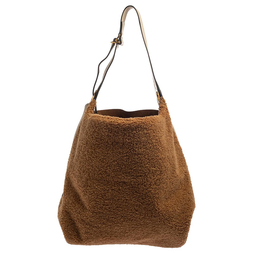 A statement hobo by Burberry that can be styled on the shoulder or as crossbody thanks to the single belted handle and the detachable shoulder strap. The hobo has a leather and fabric exterior with the brand name on the front and a spacious interior