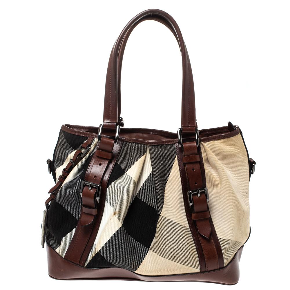 This Burberry Lowry is a harmonious fusion of excellent craftsmanship and timeless style! Meticulously made from Mega Check canvas and leather, the bag is equipped with protective metal feet at the bottom and dual top handles. The zip top closure