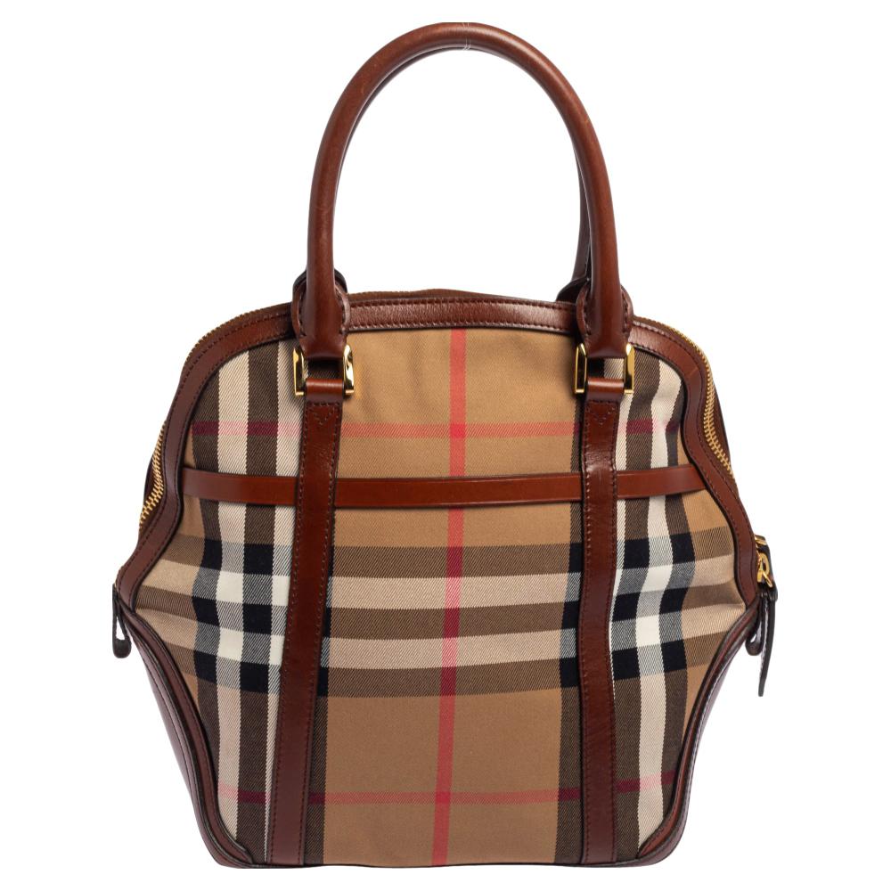 Spacious and appealing, this Orchard Bowling bag by Burberry delivers on all the qualities of an everyday bag. It has been crafted from Vintage Check canvas as well as leather and is equipped with a well-sized canvas interior, two handles, and metal