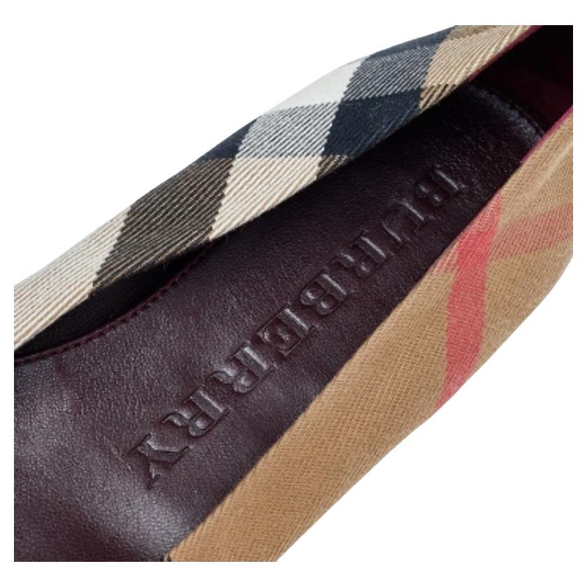 Look sharp as you wear these ballet flats from the House of Burberry. They are designed using beige-burgundy Nova Check canvas and leather on the exterior and flaunt rounded toes, gold-toned buckled accents on the front, and a slip-on style. They