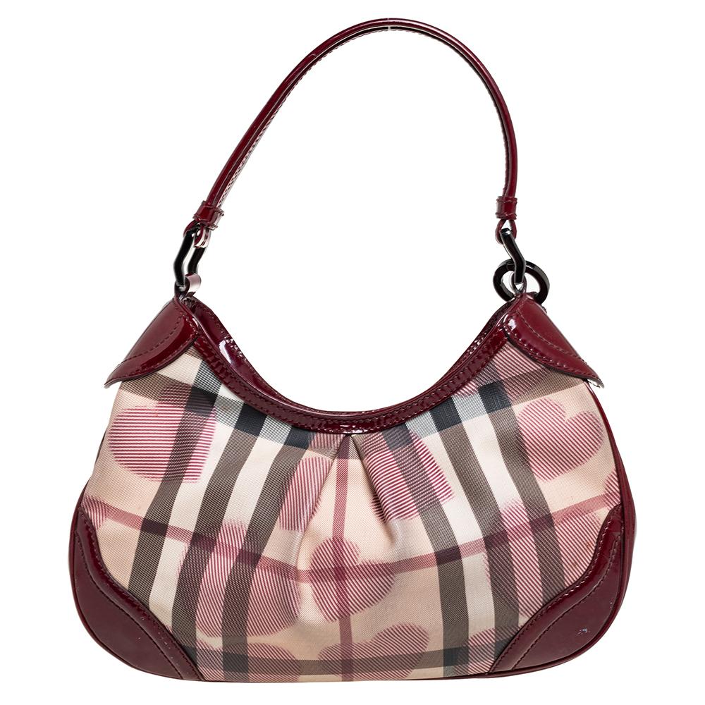Die Burberry Limited Edition Heart Hobo wurde aus Nova Check PVC sowie Lackleder gefertigt und innen mit Canvas ausgekleidet. Sein Äußeres ist wunderschön gestaltet und mit Herzen übersät. Der Reißverschluss an der Oberseite führt zu einem