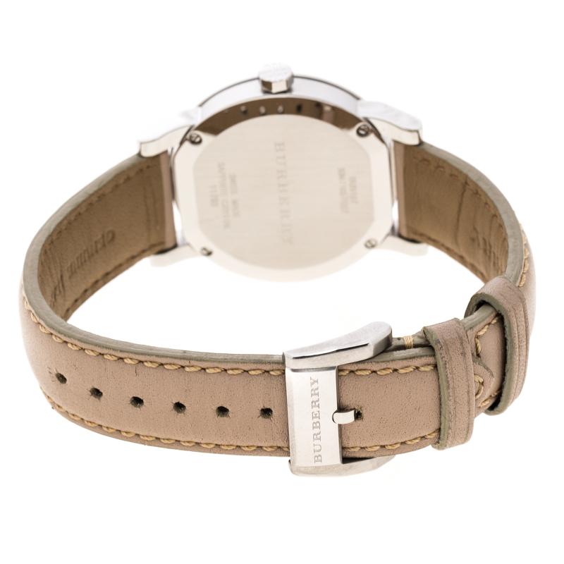 This Burberry wristwatch comes crafted in stainless steel. The rounded case holds a bezel housing a dial embossed with a checkered pattern. It features silver-tone hour index markers, slim hands and a date window at 3 o'clock. It comes with a