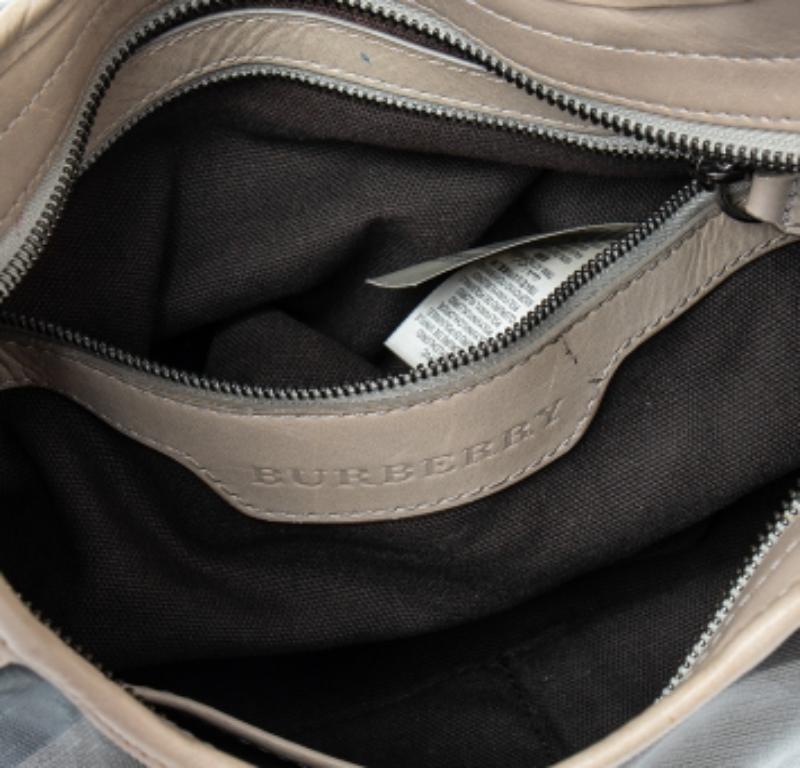 Cet adorable hobo Brooklyn de la maison Burberry est parfait pour transporter vos essentiels de fille avec style. Il présente un magnifique extérieur en toile enduite à carreaux accentué par des garnitures en cuir et un h en cuir roulé. La partie