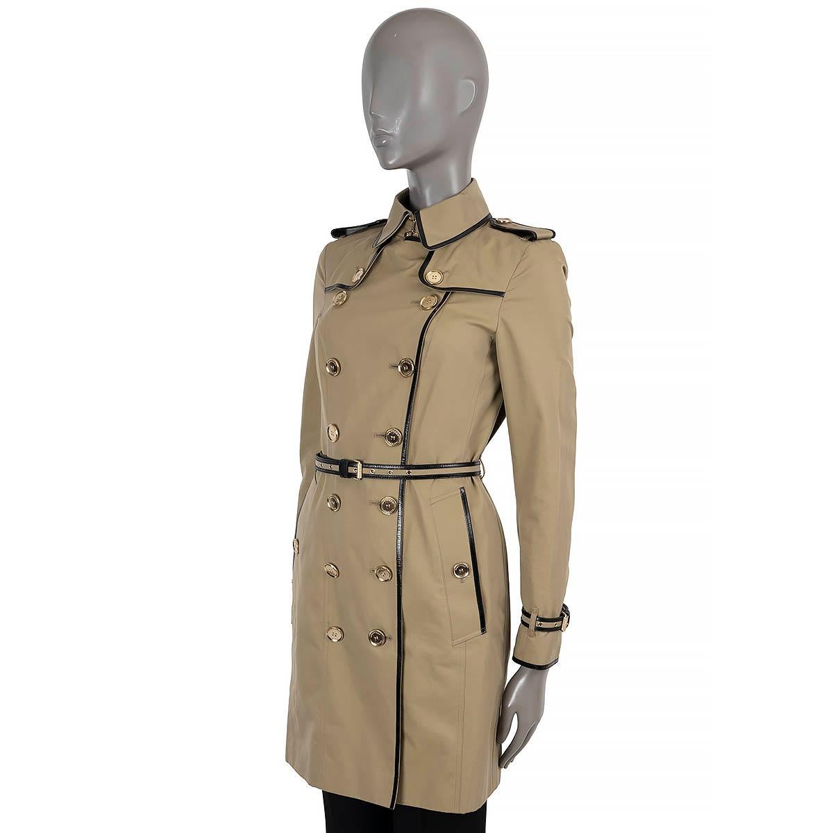 Gabardina Burberry London 100% auténtica de algodón beige (100%). Presenta ribetes de charol negro, charreteras, solapas antitormenta en el pecho y la espalda, bolsillos abotonados en la cintura y cinturones de charol a rayas en los puños y la