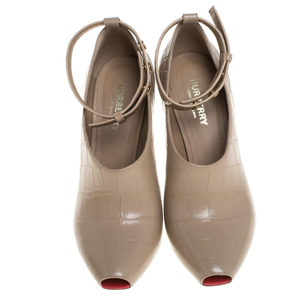 Simply stunning, these Jermyn Burberry pumps will never fail to lift you up gracefully! They have been crafted from beige croc-embossed leather and feature a peep-toe silhouette. They flaunt gold-tone buttoned ankle cuffs and come endowed with