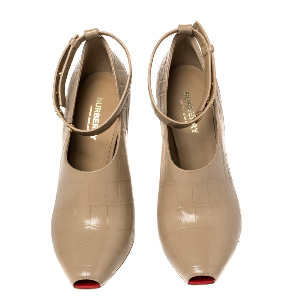 Simply stunning, these Jermyn Burberry pumps will never fail to lift you up gracefully! They have been crafted from beige croc-embossed leather and feature a peep-toe silhouette. They flaunt gold-tone buttoned ankle cuffs and come endowed with