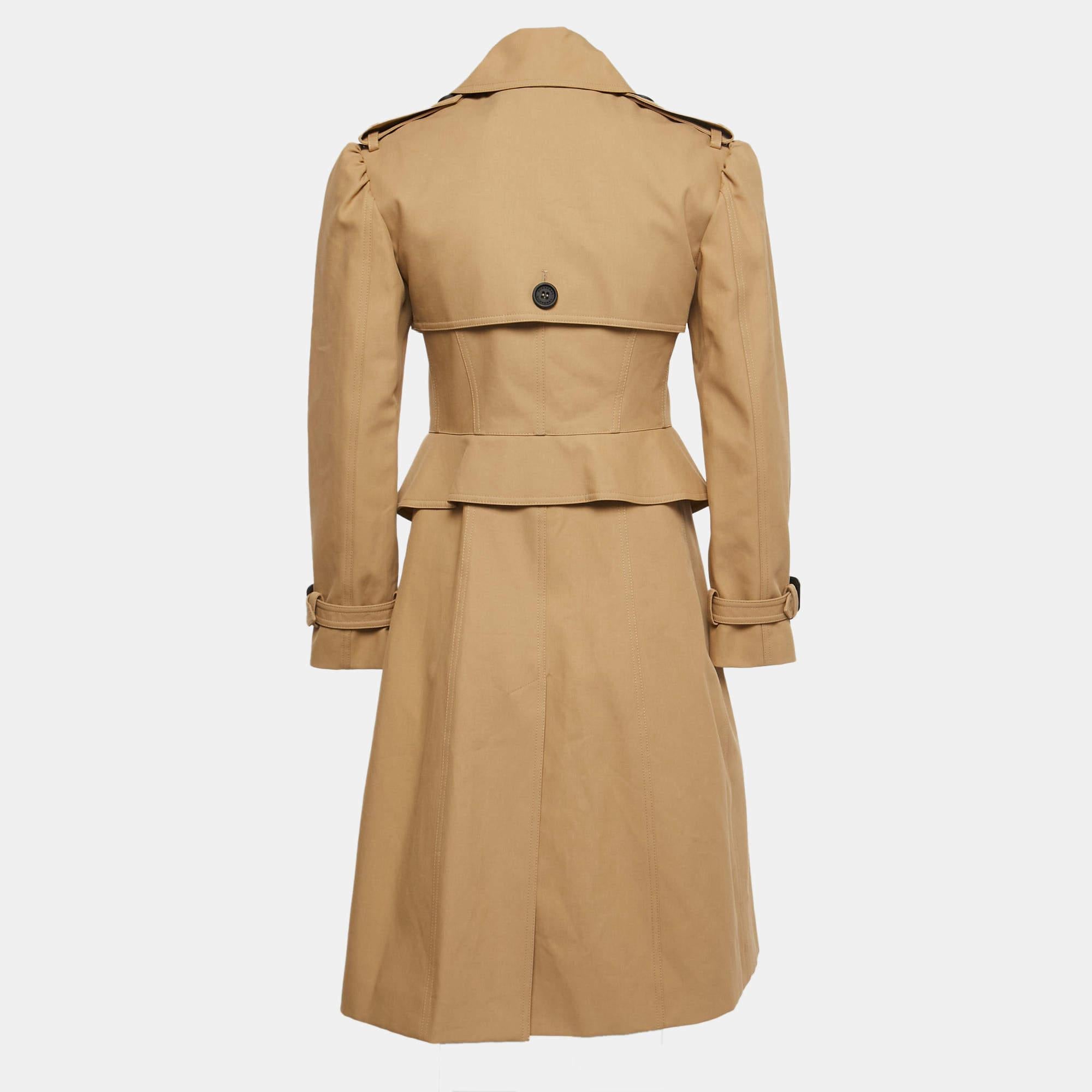 The Burberry trench coat is an iconic fashion staple. Crafted from durable gabardine fabric, it features a classic double-breasted design, signature check lining, adjustable belt, and versatile beige hue. This timeless piece combines style and