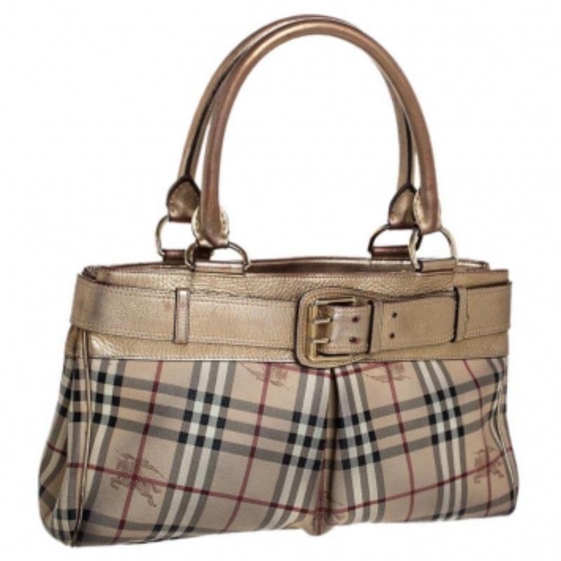 Adorned with the classic Burberry Haymarket check canvas, this Burberry Bridle tote is accented with metallic gold leather. It is detailed with a huge gold-tone buckled belt on the front and rolled leather top handles. The open top leads to a