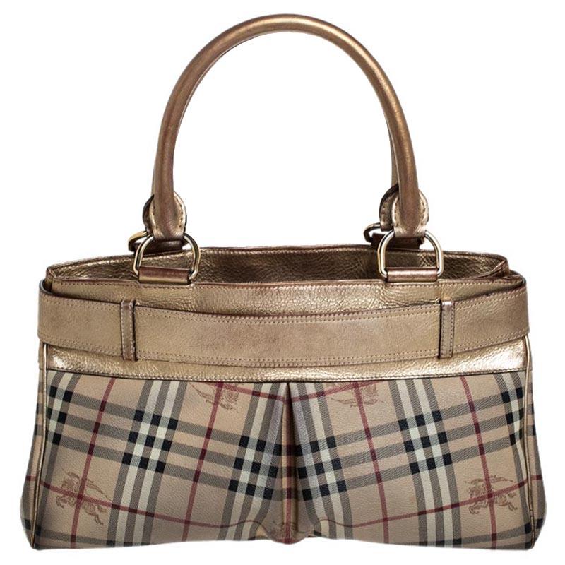 Adorned with the classic Burberry Haymarket check canvas, this Burberry Bridle tote is accented with metallic gold leather. It is detailed with a huge gold-tone buckled belt on the front and rolled leather top handles. The open top leads to a