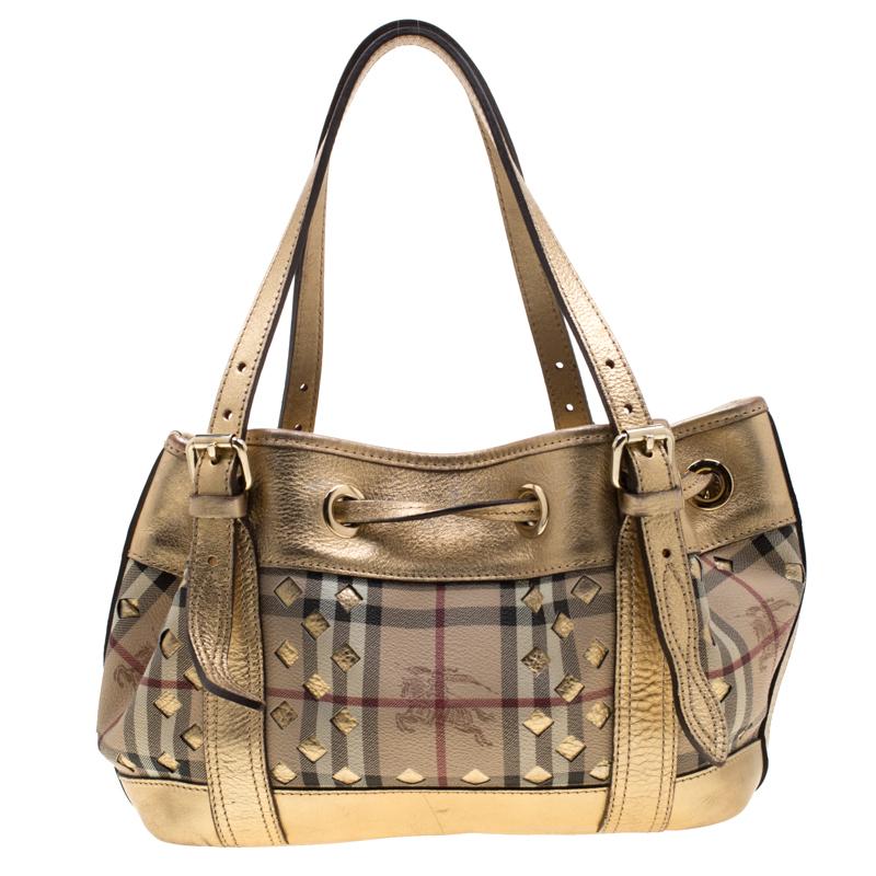 This Burberry handbag showcases a refreshing design. The bag is crafted from Haymarket check PVC and is enhanced with a cutout pattern and leather trims. It has a drawstring closure that opens to a canvas lined interior and it can be held using the