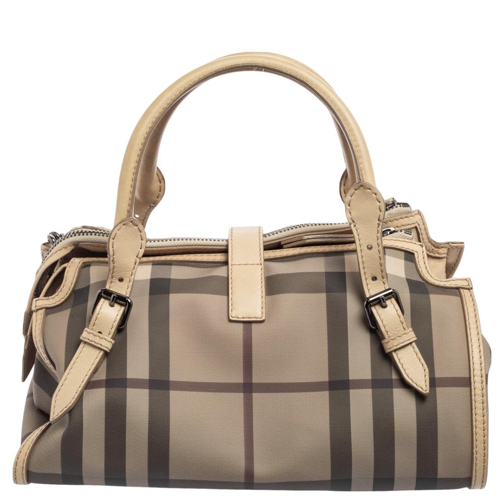 Spacious and practical, this bowling bag is from Burberry. It has been crafted from PVC in their signature Smoked check and accented with black-tone hardware. It is equipped with two rolled handles and a band flap with a turn-lock closure that