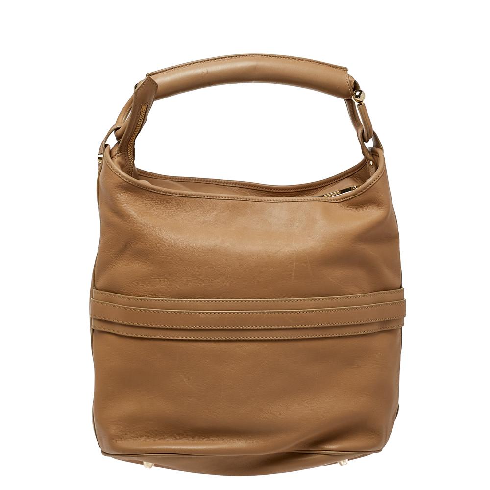 Burberry's equestrian sensibilities come alive in this hobo that is practical and stylish. Crafted from leather in a beige shade, it features a horsebit motif, a spacious interior, and a single handle. This bag can be carried for every day use.

