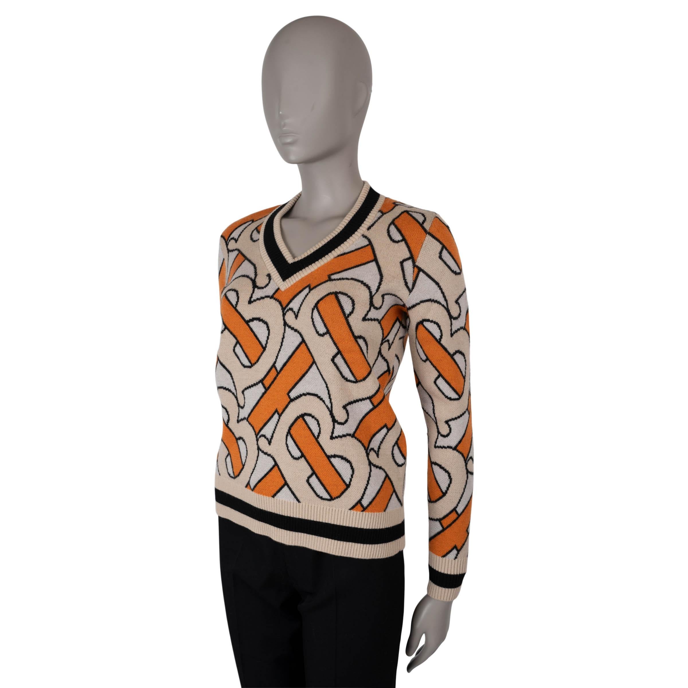 Ce pull cricket 100 % authentique en laine beige pâle est orné d'un monogramme TB intarsia orange et beige, qui ajoute une touche de signature à ce modèle classique. Ce pull est doté d'un col en V et rehaussé de bordures en tricot côtelé à rayures