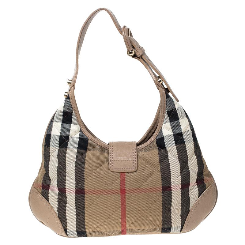 Gehen Sie stilvoll aus mit dieser Version der Brooke Hobo des britischen Luxus-Modehauses Burberry. Die aus House Check Canvas und Leder gefertigte Tasche verfügt über einen einzigen Henkel und eine mit einem Vorhängeschloss versehene Frontklappe.