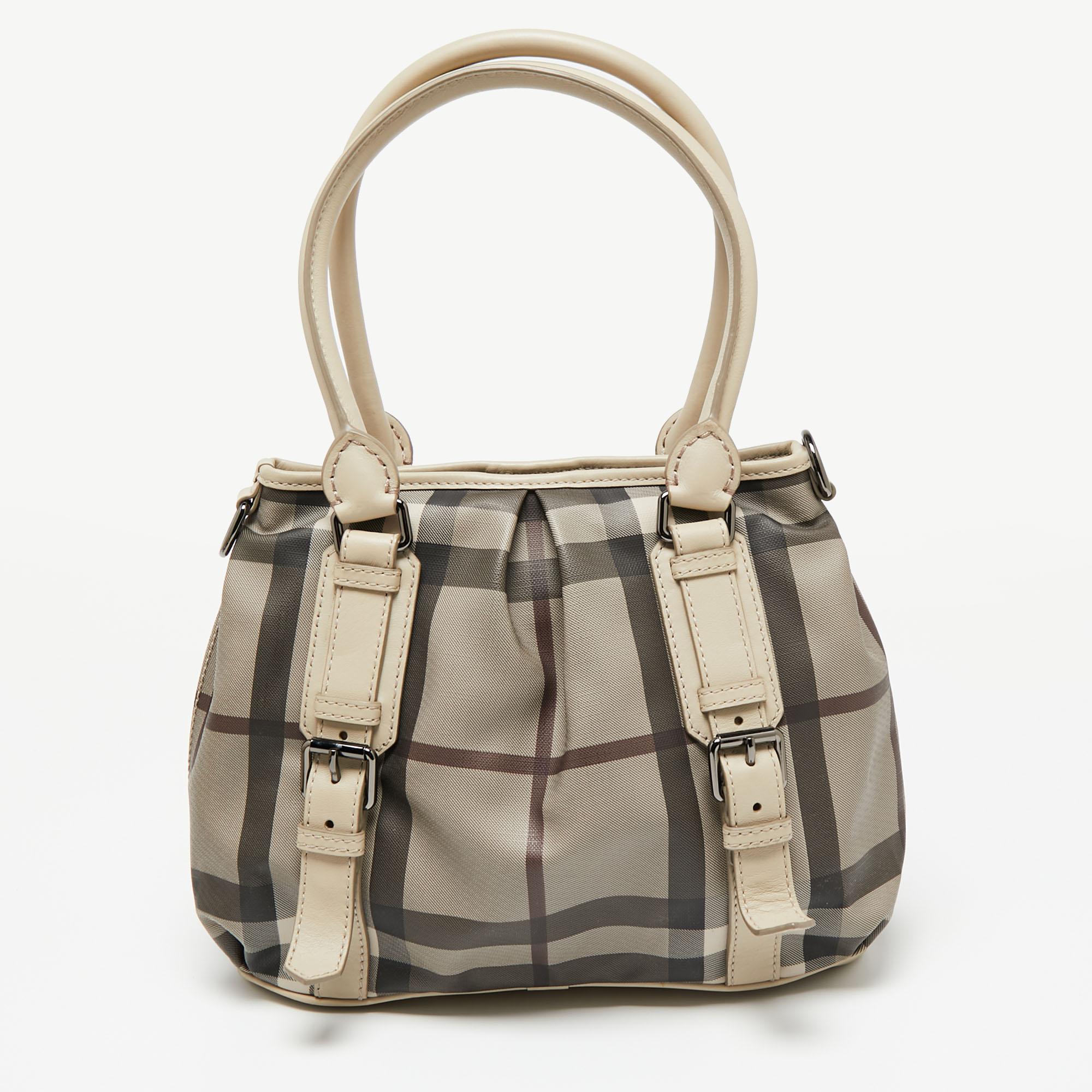 Charming and contemporary, this Northfield tote is from Burberry. It is created from the Check PVC and flaunts two rolled handles, a detachable shoulder strap, and a well-sized canvas interior. The beige exterior is also equipped with buckle