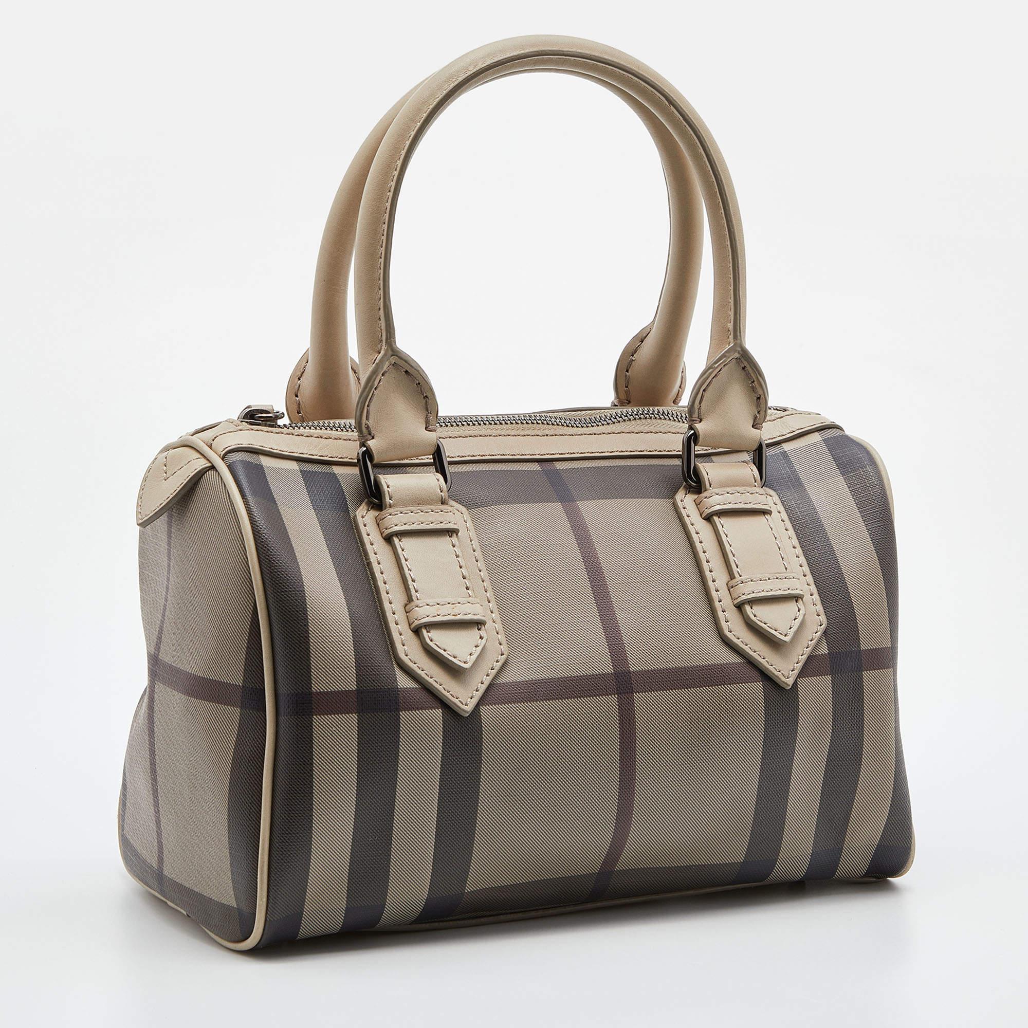 Spacious and captivating, this Chester Boston bag is from Burberry. It has been crafted from their signature Smoked check PVC and accented with leather trims and silver-tone hardware. It is equipped with a well-sized canvas interior, two rolled