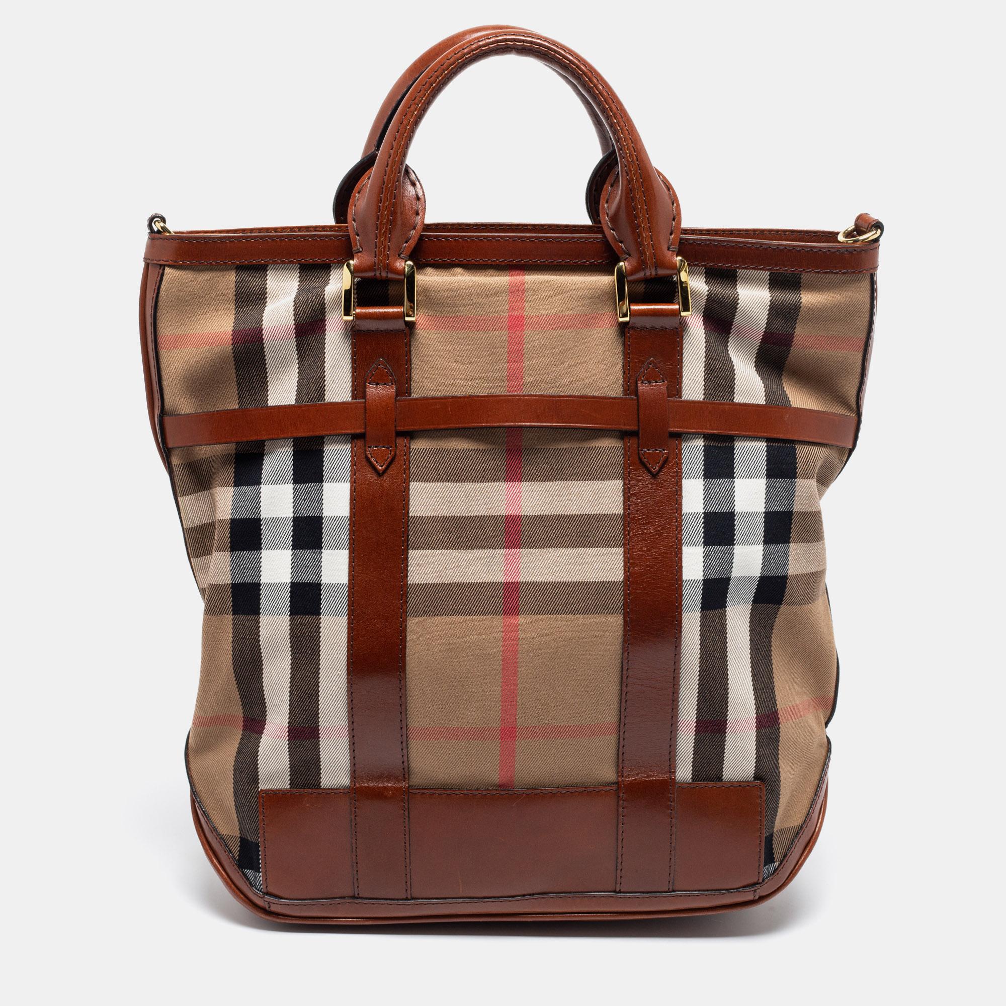 This stylish and functional tote comes from the house of Burberry. Crafted in Italy, this bag has been made from leather and House Check canvas. It is styled with dual handles, a shoulder strap, and gold-tone hardware. It opens to a fabric interior
